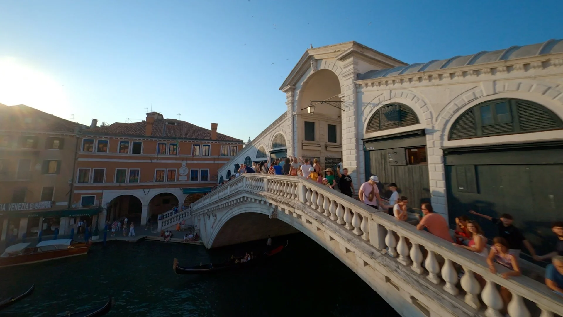 Aerial drone view of Venice’s Rialto Bridge over the Grand Canal, surrounded by historic waterfront buildings and the dense architecture of central Venice.