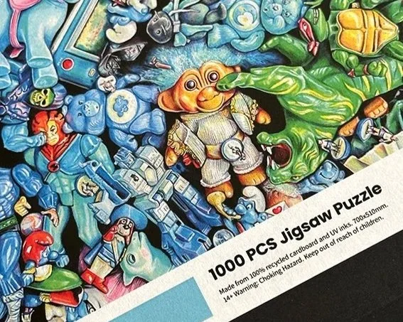 Close-up of a jigsaw puzzle featuring cartoon characters and toys, with a white banner saying '1000 PCS Jigsaw Puzzle'.