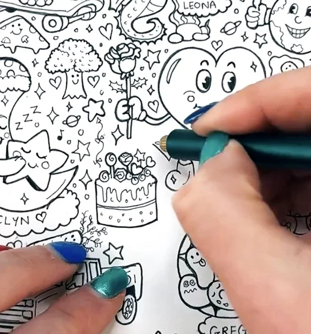 Close-up of Gemma Doodle Drawing live doodles on TikTok.. The drawing contains cartoon characters, a birthday cake, stars, a heart, a pizza, and a smiling face, with some names like 'Leona' and 'Clyn' written on it.