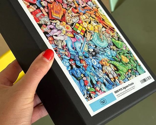Box containing 1000-piece jigsaw puzzle featuring a colorful, busy illustration of various characters and objects.