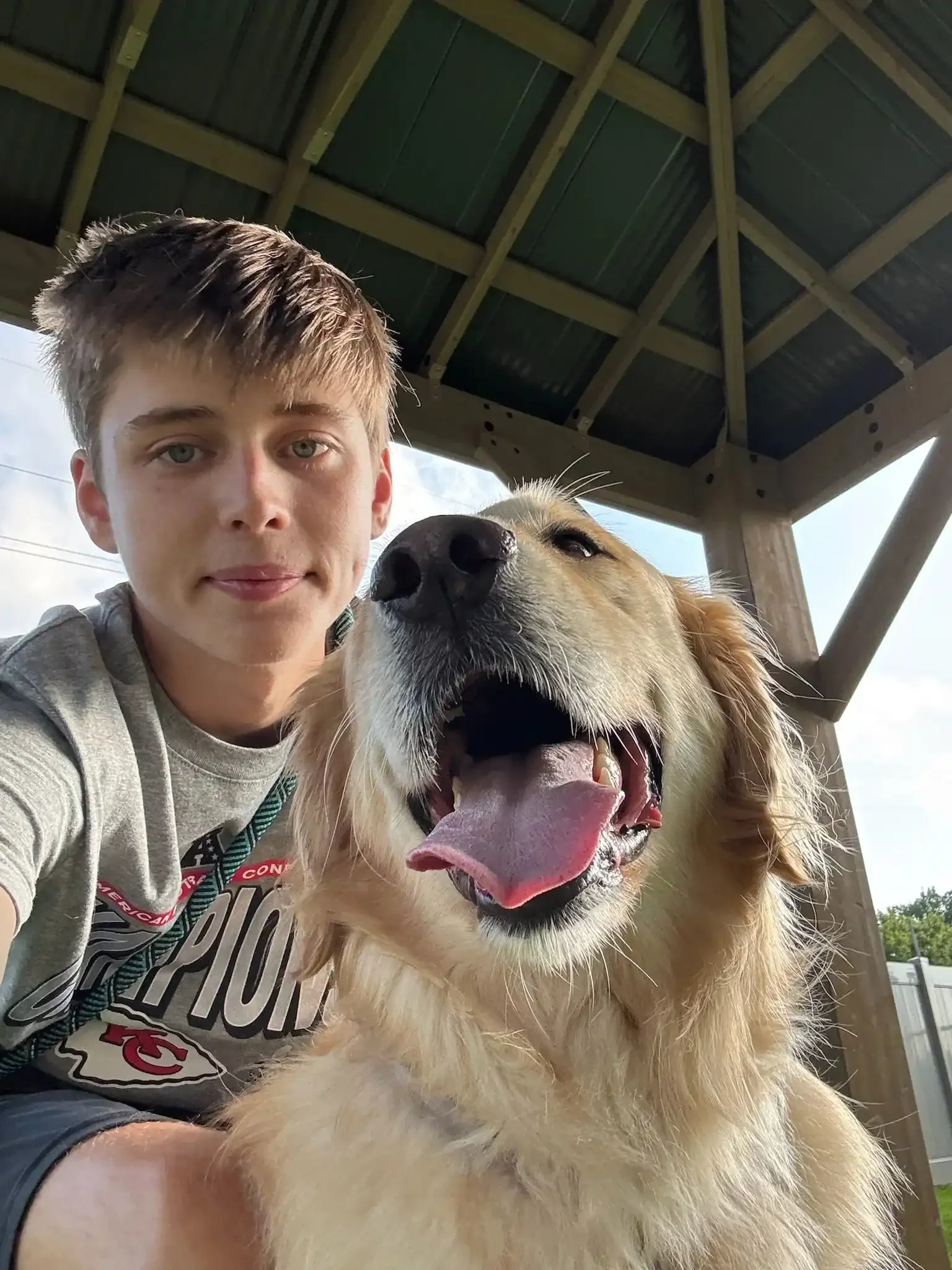 A young boy and a golden retriever taking a selfie together outdoors during a day at dog boarding in Omaha.