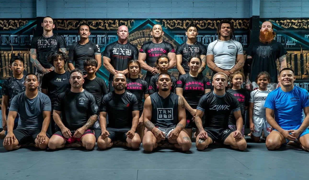 Group photo of mixed martial arts fighters and children in a gym.
