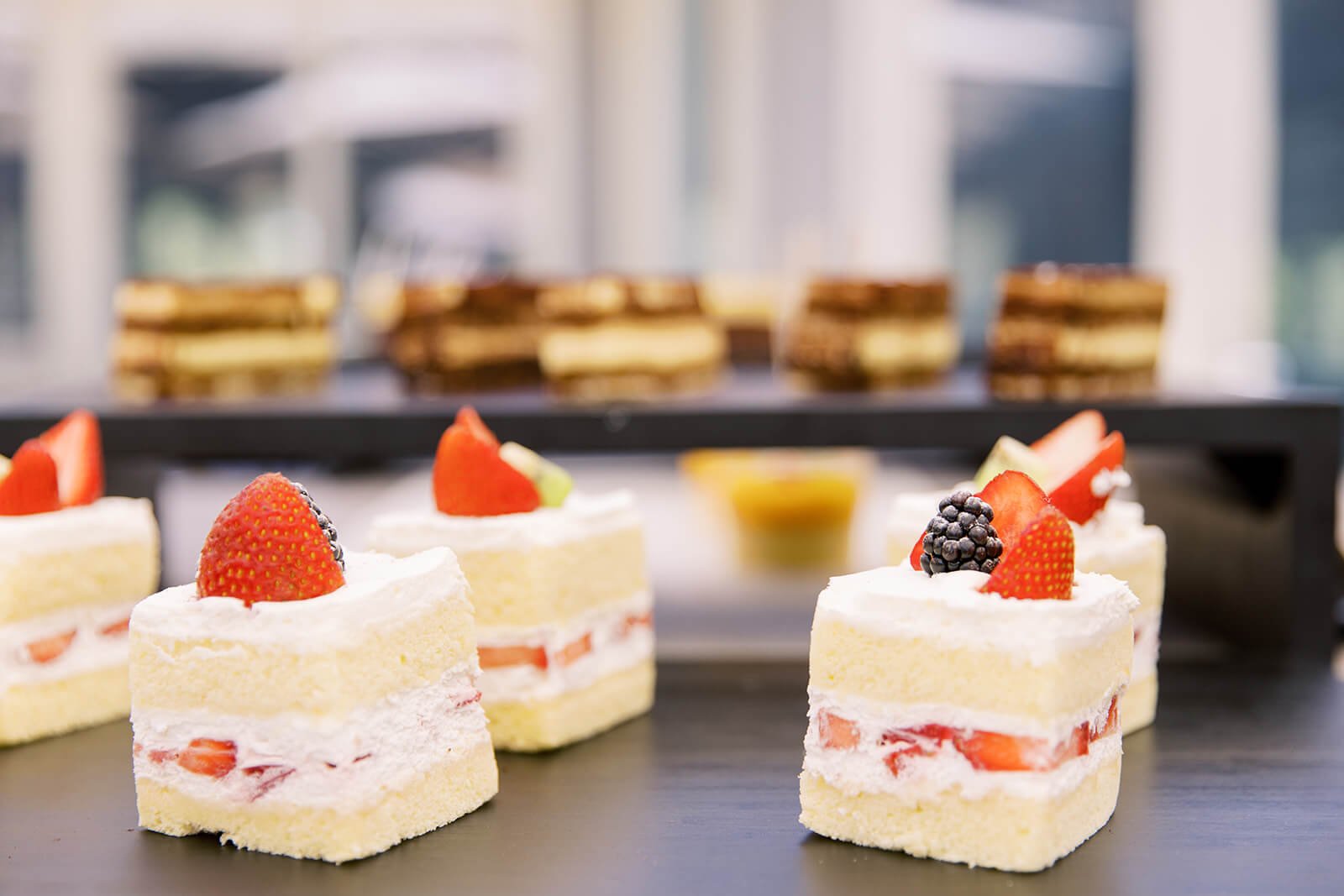 Small strawberry shortcake squares with cream and fruit pieces on a tray.