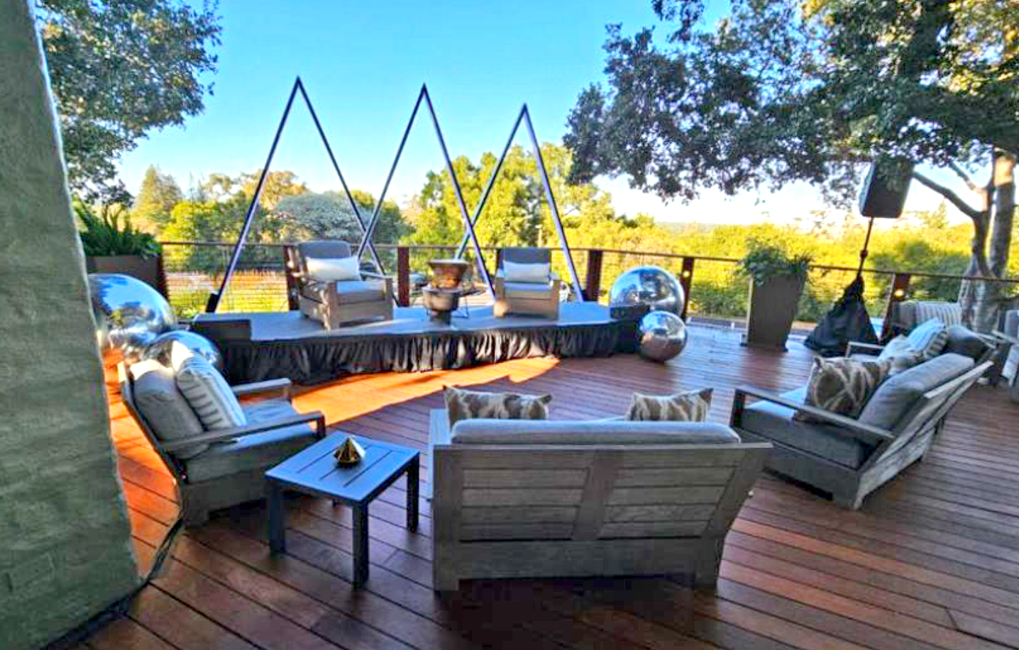 Outdoor seating at the Tree Deck at The Quad Conference Center with cushioned chairs, a small table, and decorative metallic spheres.