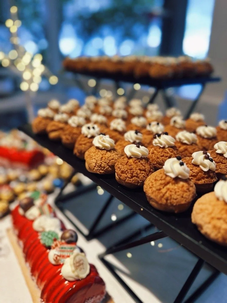 Rows of cream-topped pastries arranged neatly on a display stand.