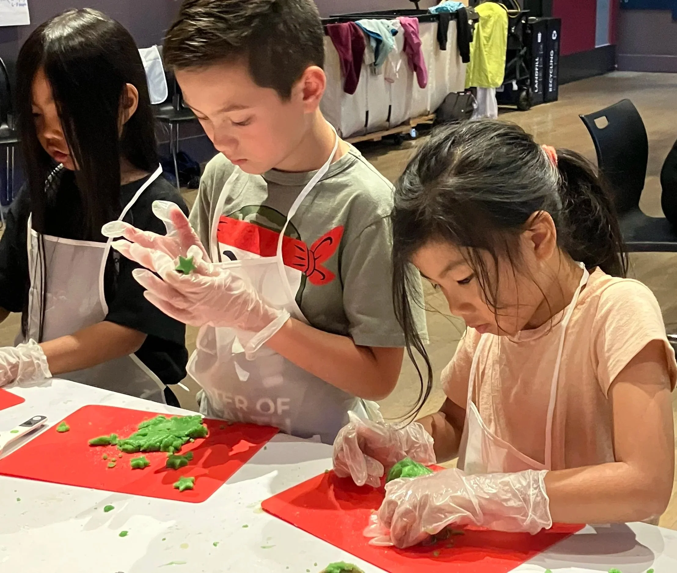 Three kids forming dough into pandan cookies