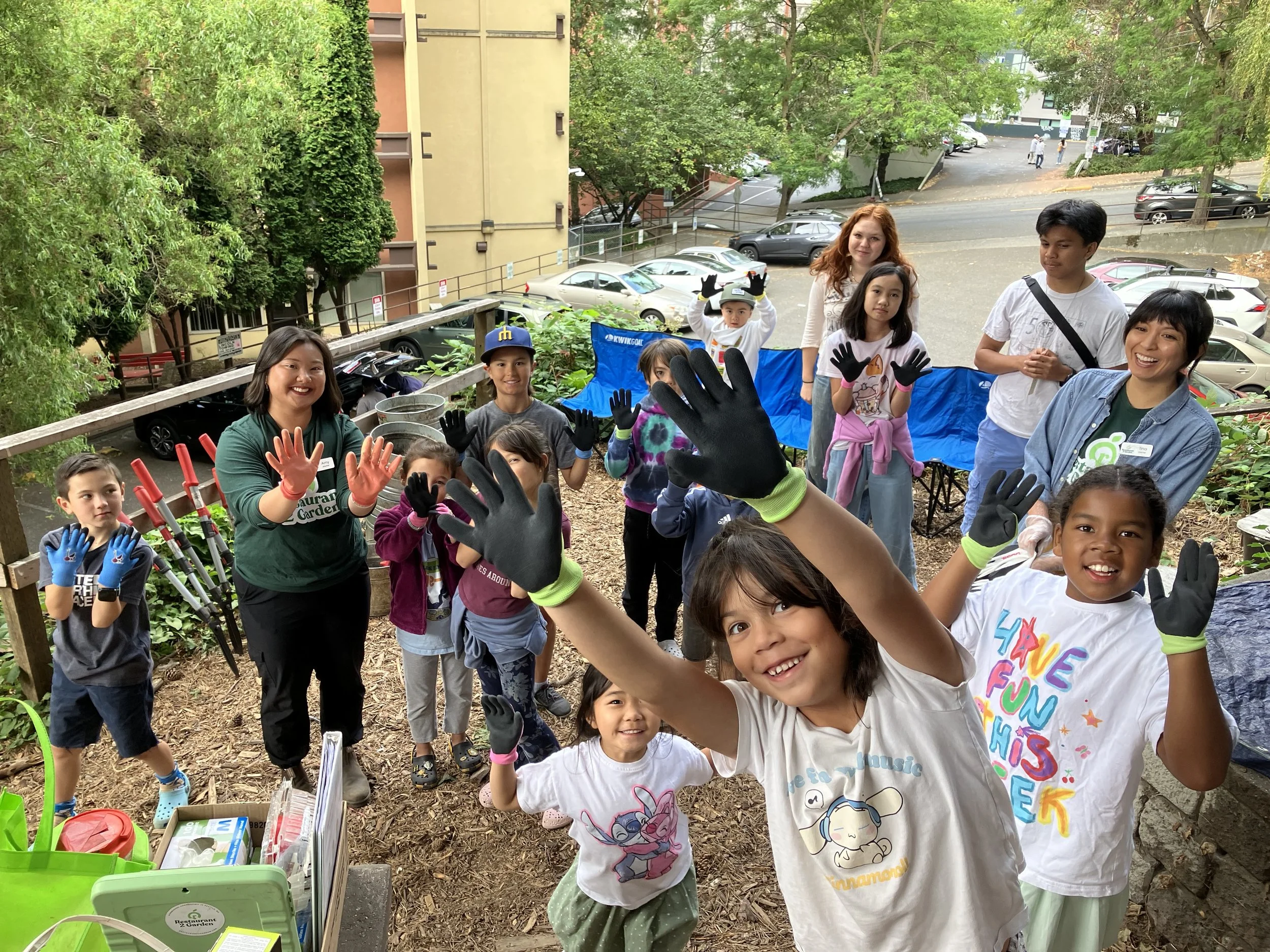 Kids are smiling and showing their hands have sturdy garden gloves.
