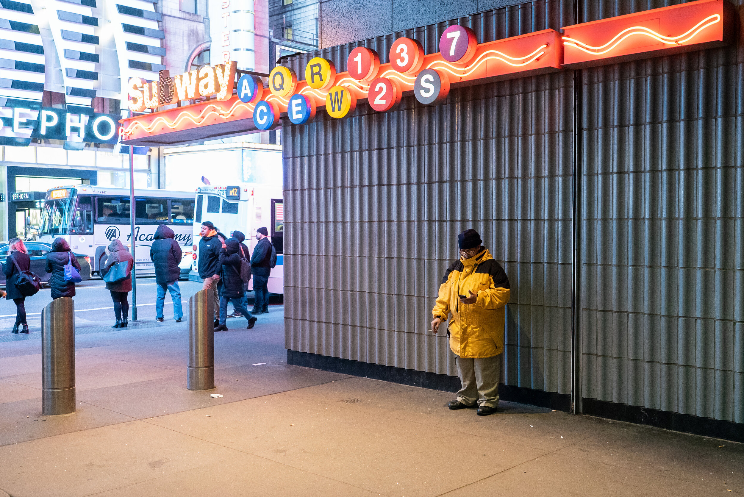 Smoker in yellow coat under Times Square subway sign in Manhattan | 2018