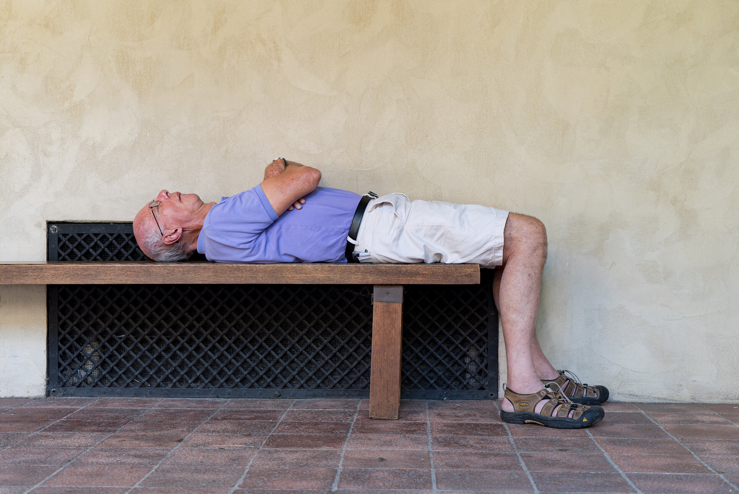 Man sleeping on a bench at The Met Cloisters | 2017