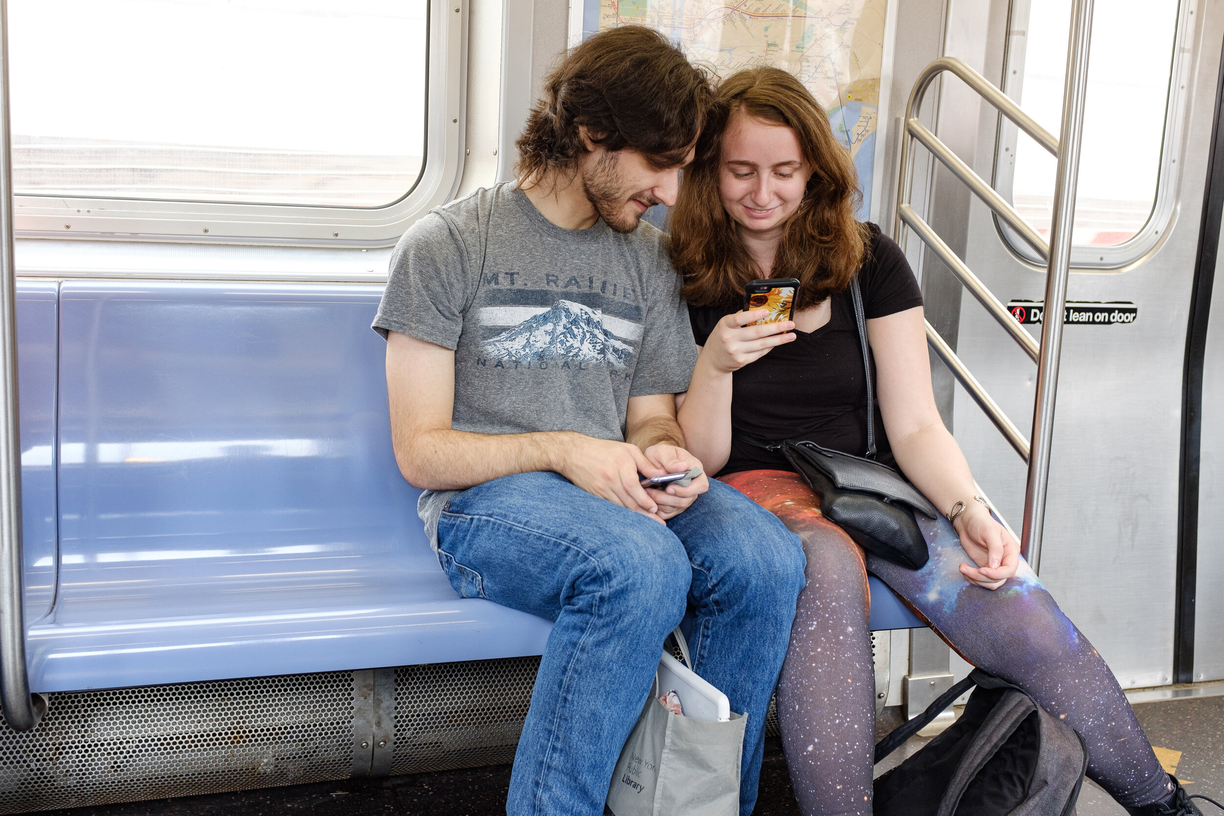 A couple reading off smartphone on NYC subway | 2018