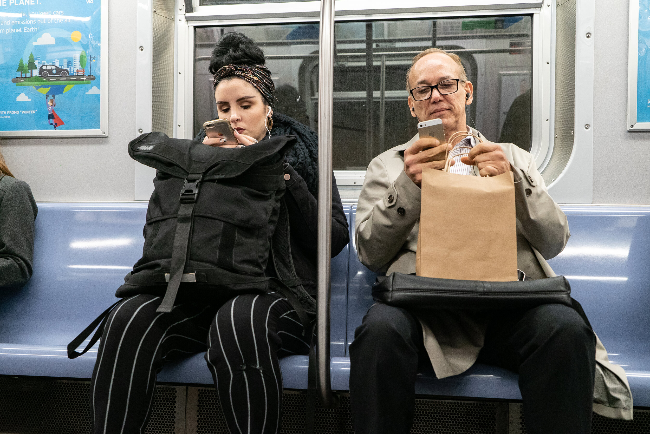 Two screen-locked subway riders sitting side-by-side | 2018