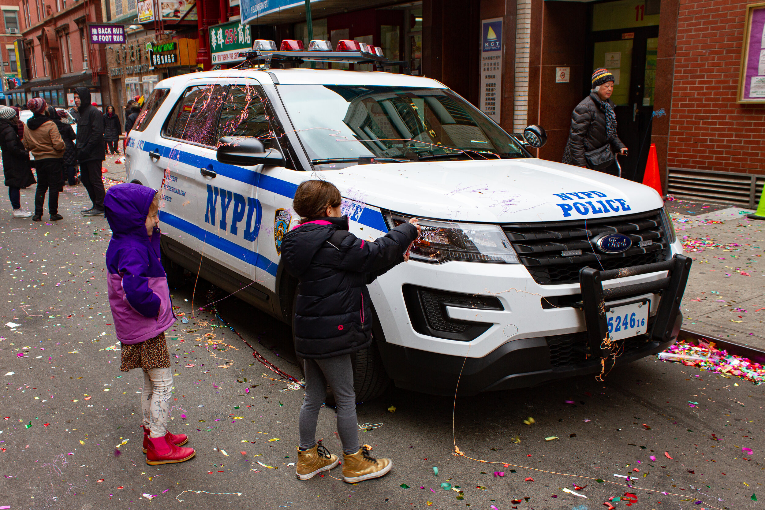 Two young girls spray a NYPD police car with silly string in Chinatown, Manhattan | 2017