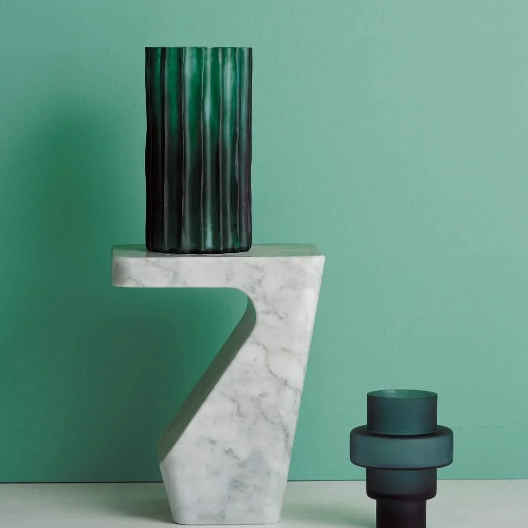 Sculptural forms meet luminous materials.​
Stump, the white Carrara marble side table by Pierre Charpin, dialogues with Bu&eacute;e, the indigo blue blown glass vase by @martin_hirth , and the Ribbed Vase in green. A trio where noble materials and bu