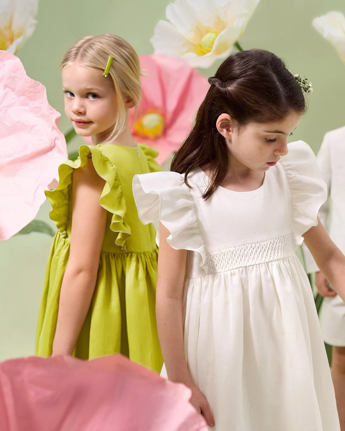 A ceremony garden story.🍃​

In earthy moss green and soft white linen, our new ceremony dresses echo the gentle tones of a summer garden. Ruffled sleeves and hand-embroidered smocking bring a timeless elegance to special occasions.​

Explore in stor