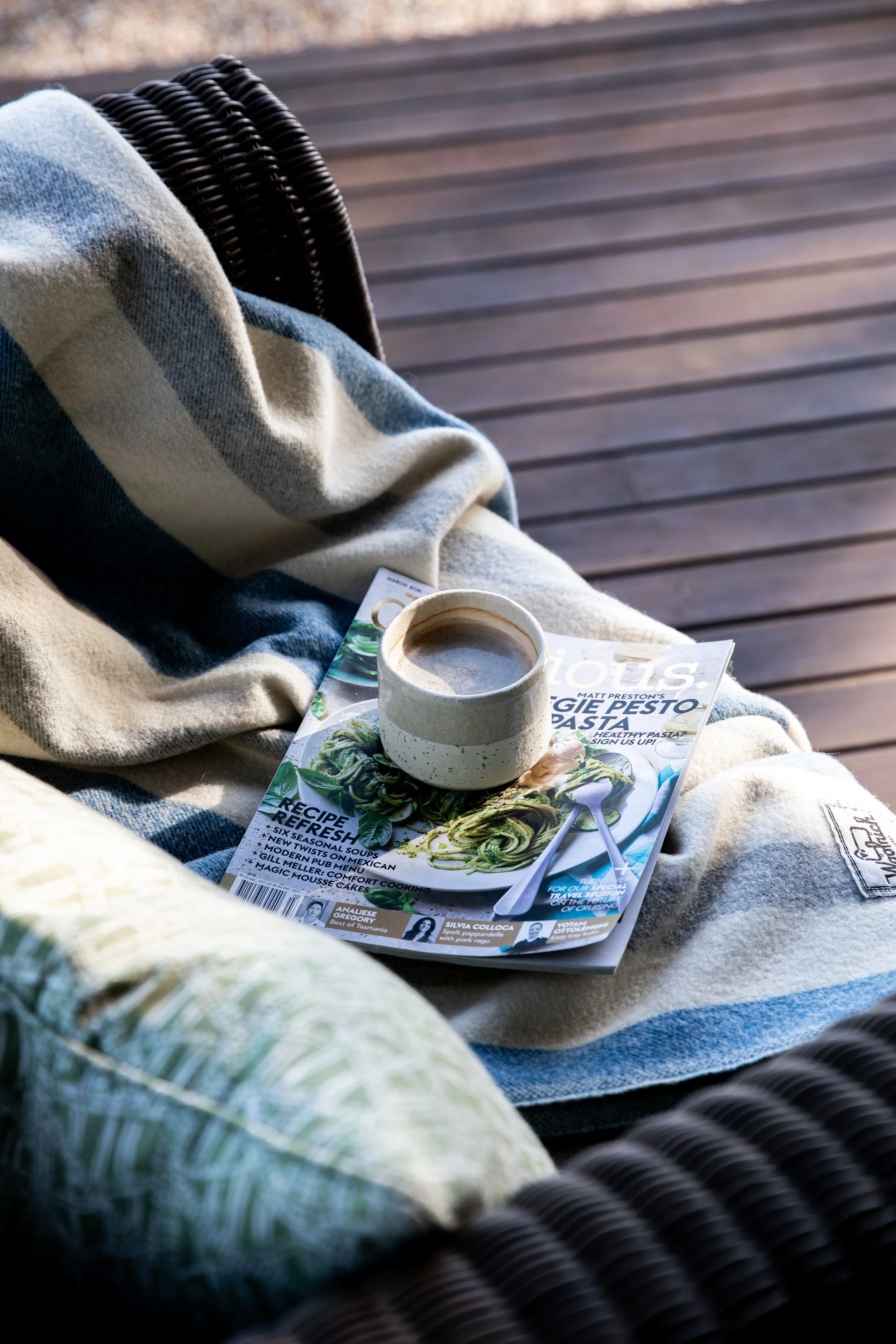 Coffee on magazine on chair with blanket