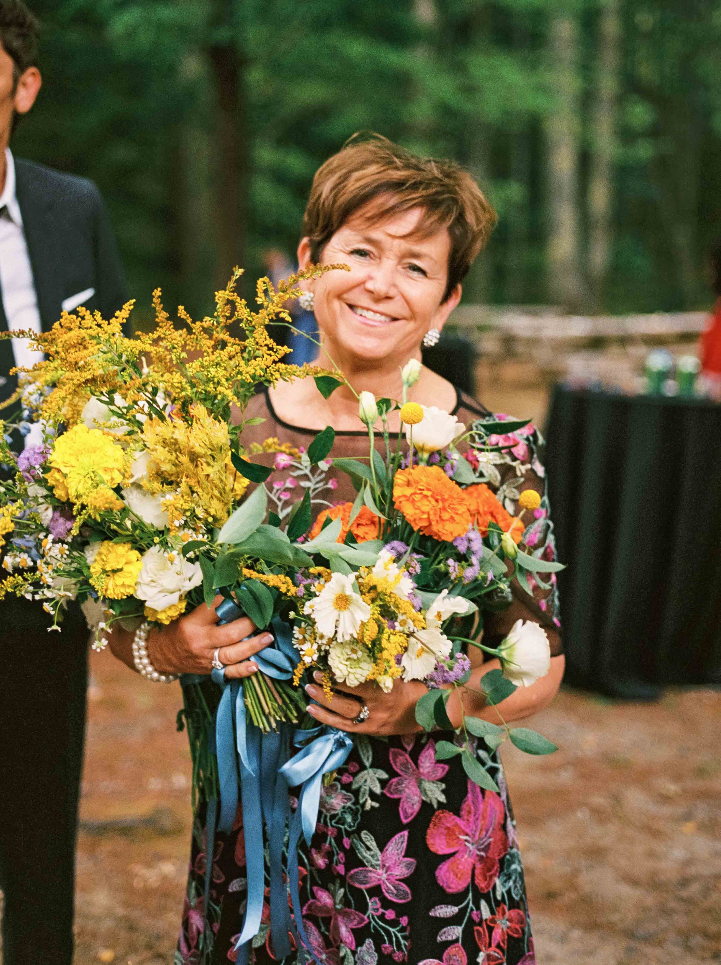 Grooms mother smiling at the camera with a lot of flowers in Maine