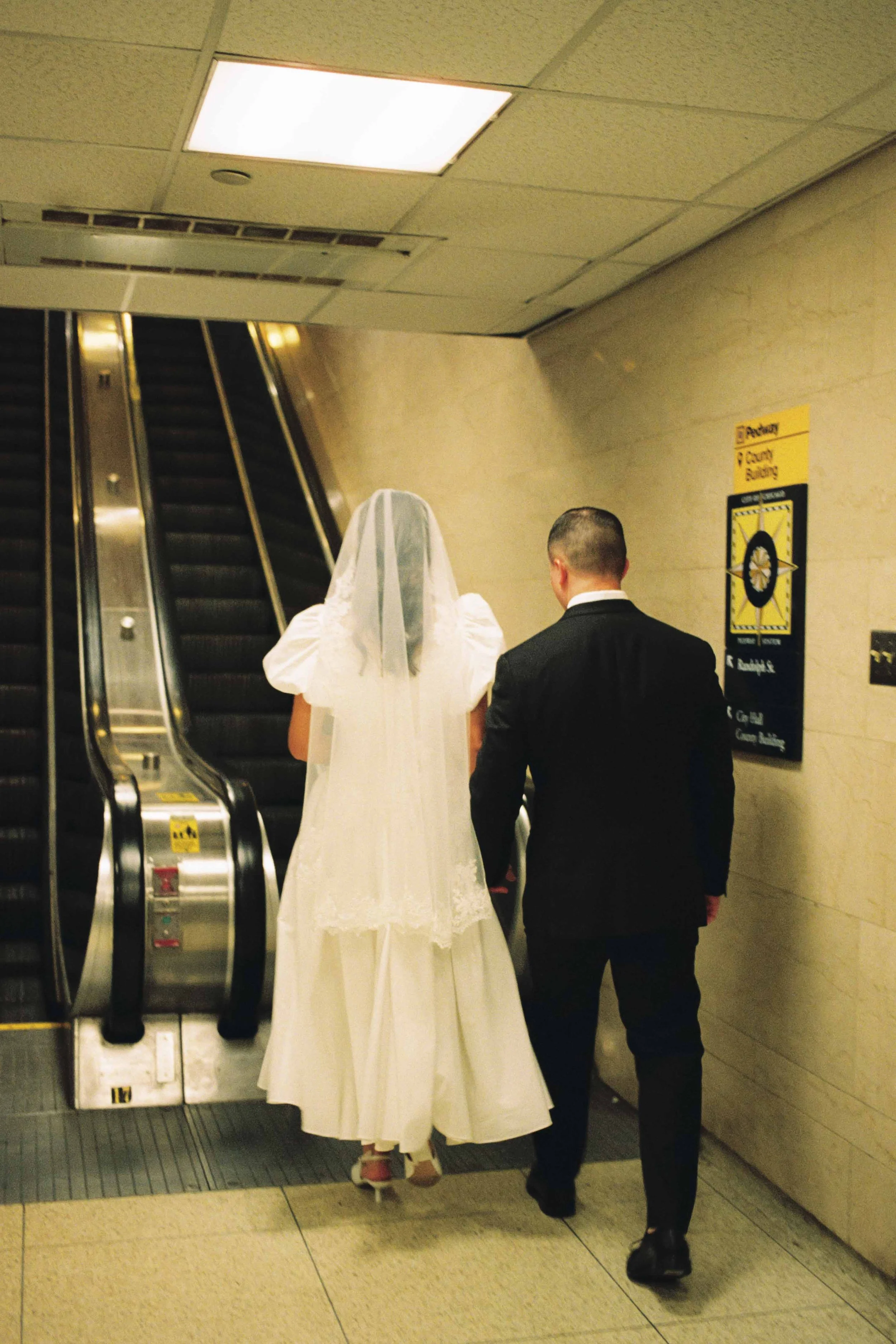 Couple walking up an esculator after getting married at Chicago City Hall