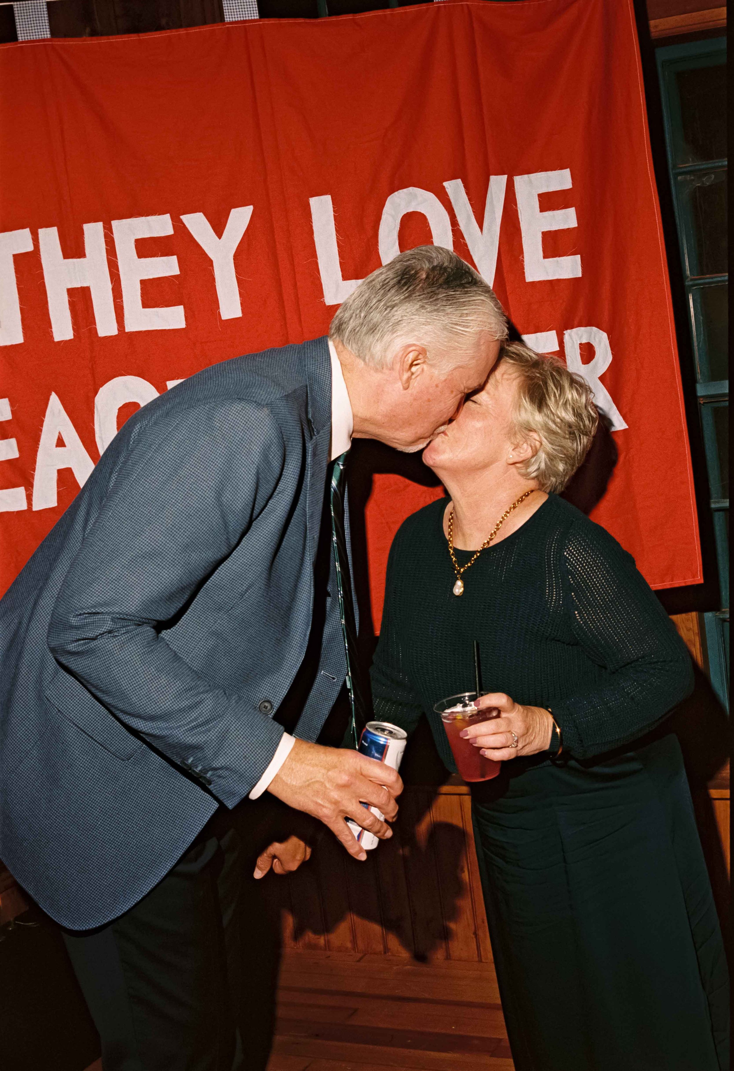Grandparents kissing in front of a homemade wedding banner