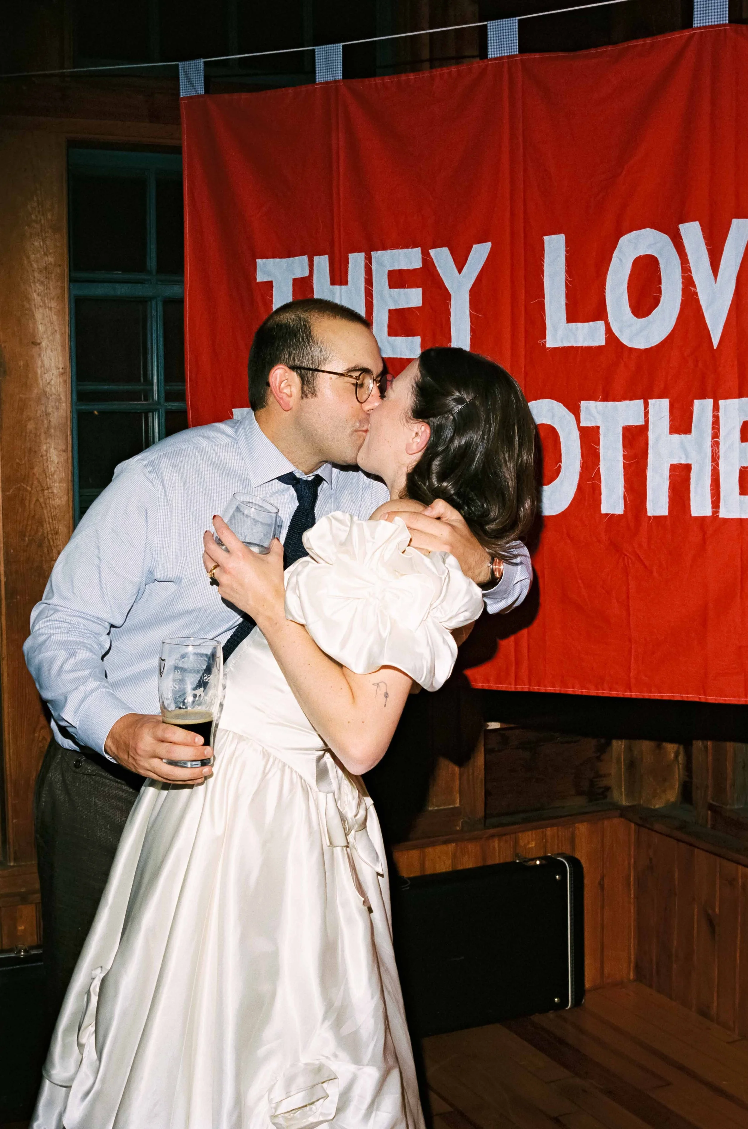Bride and Groom kissing in front of their homemade wedding banner at their Maine wedding