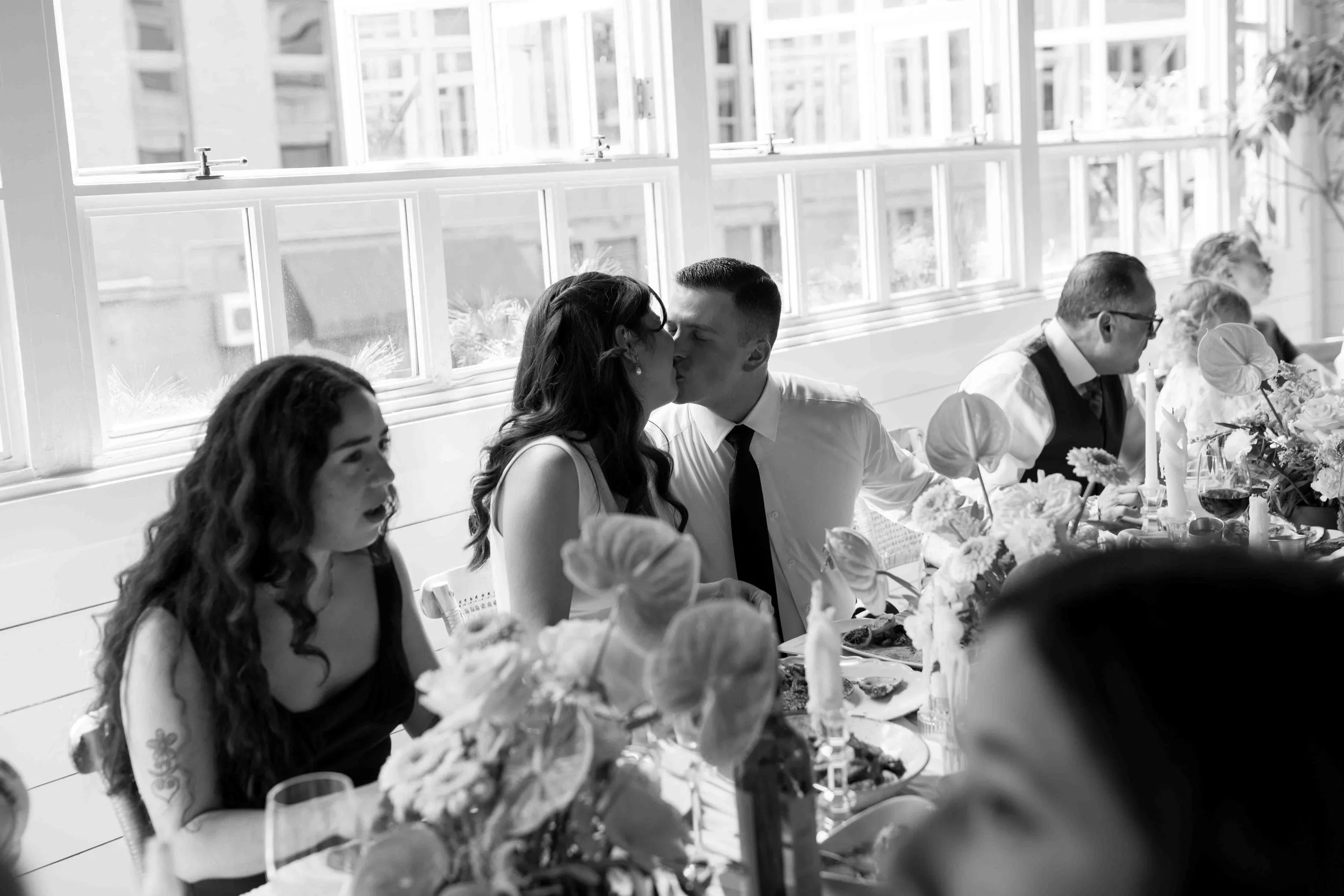 Candid of wedding couple kissing at lunch on their wedding day