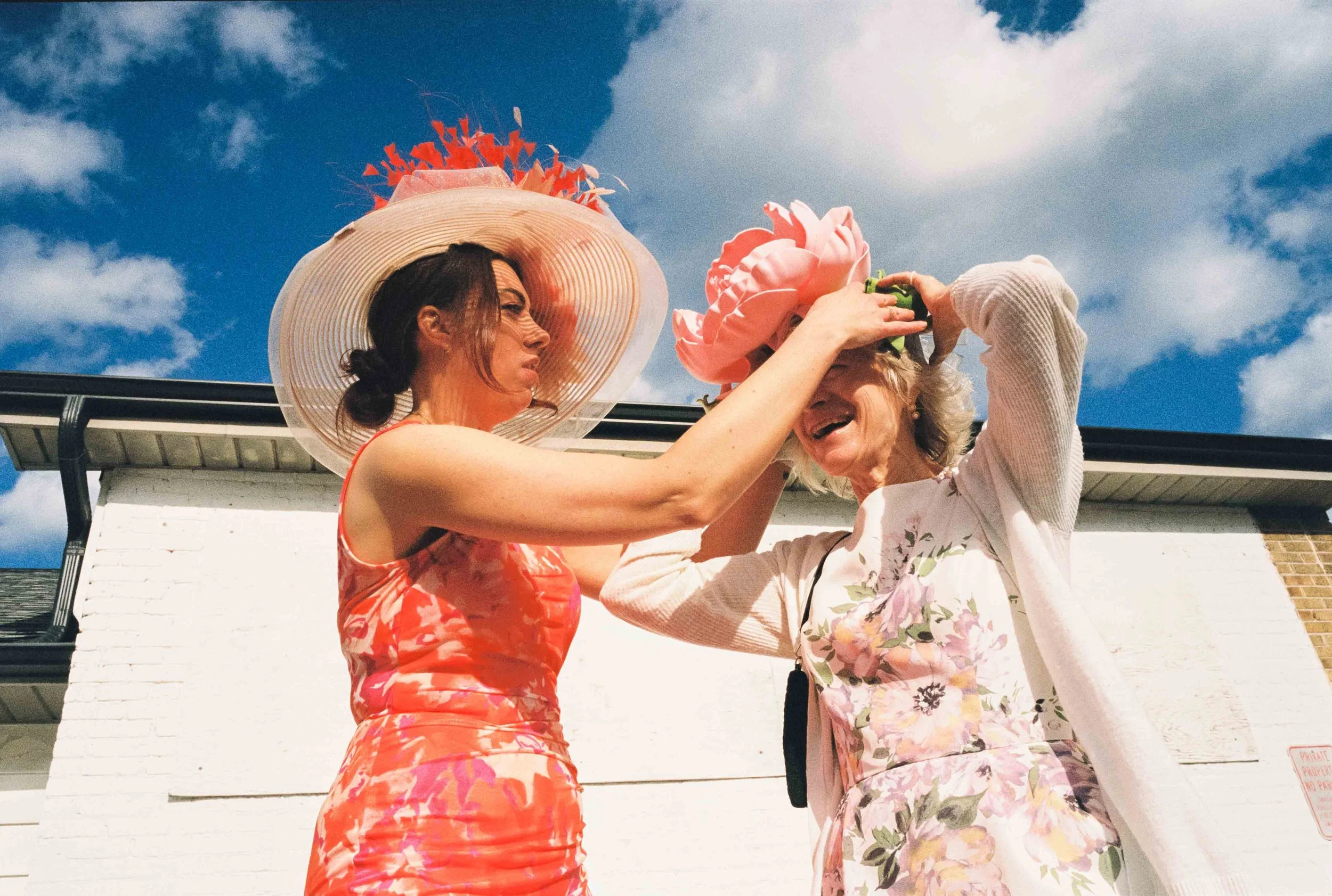 Two women on the Kentucky Derby Day outside helping with their hats
