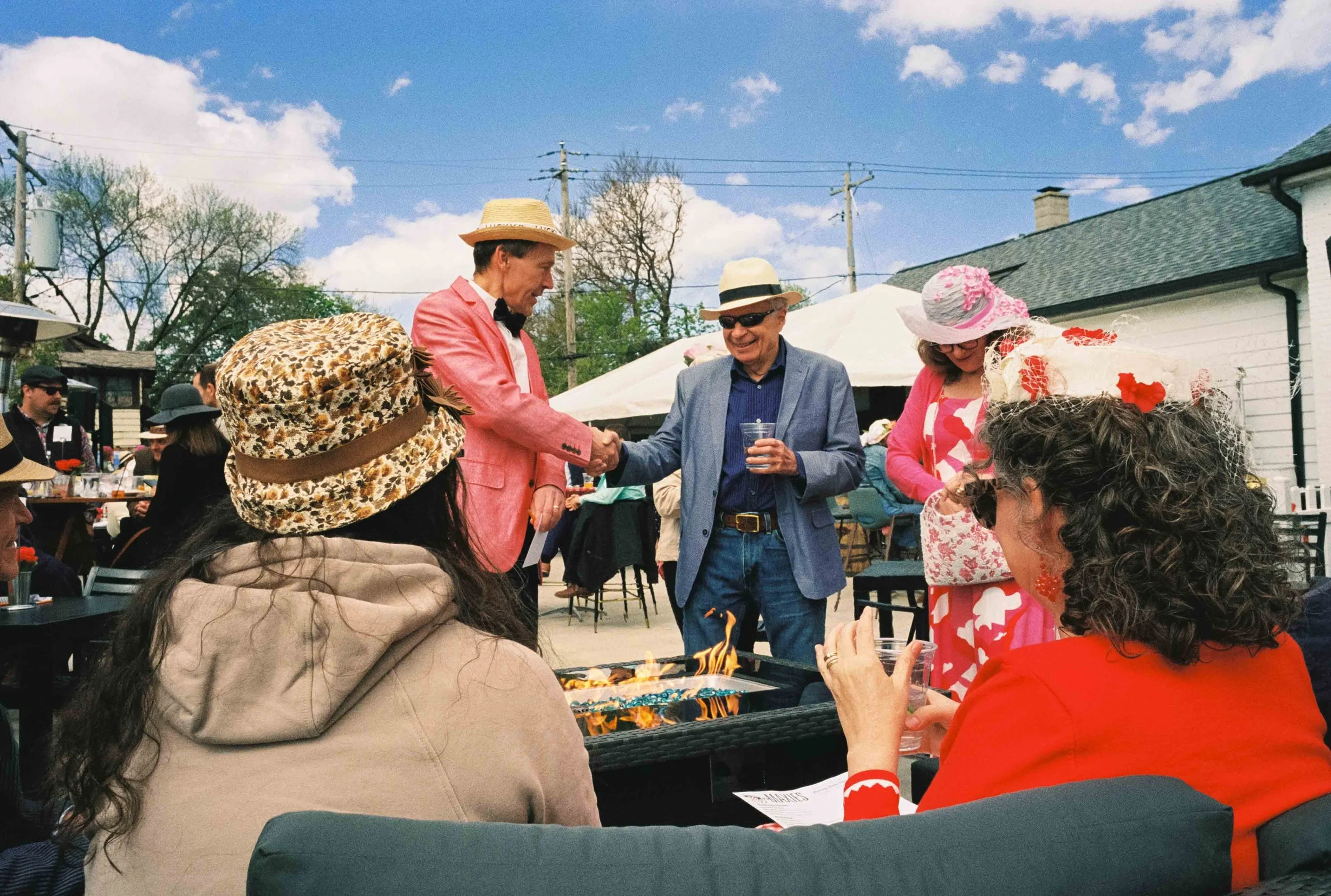 Two men shaking hands and women talking on the Kentucky Derby Day Party at Maxie's