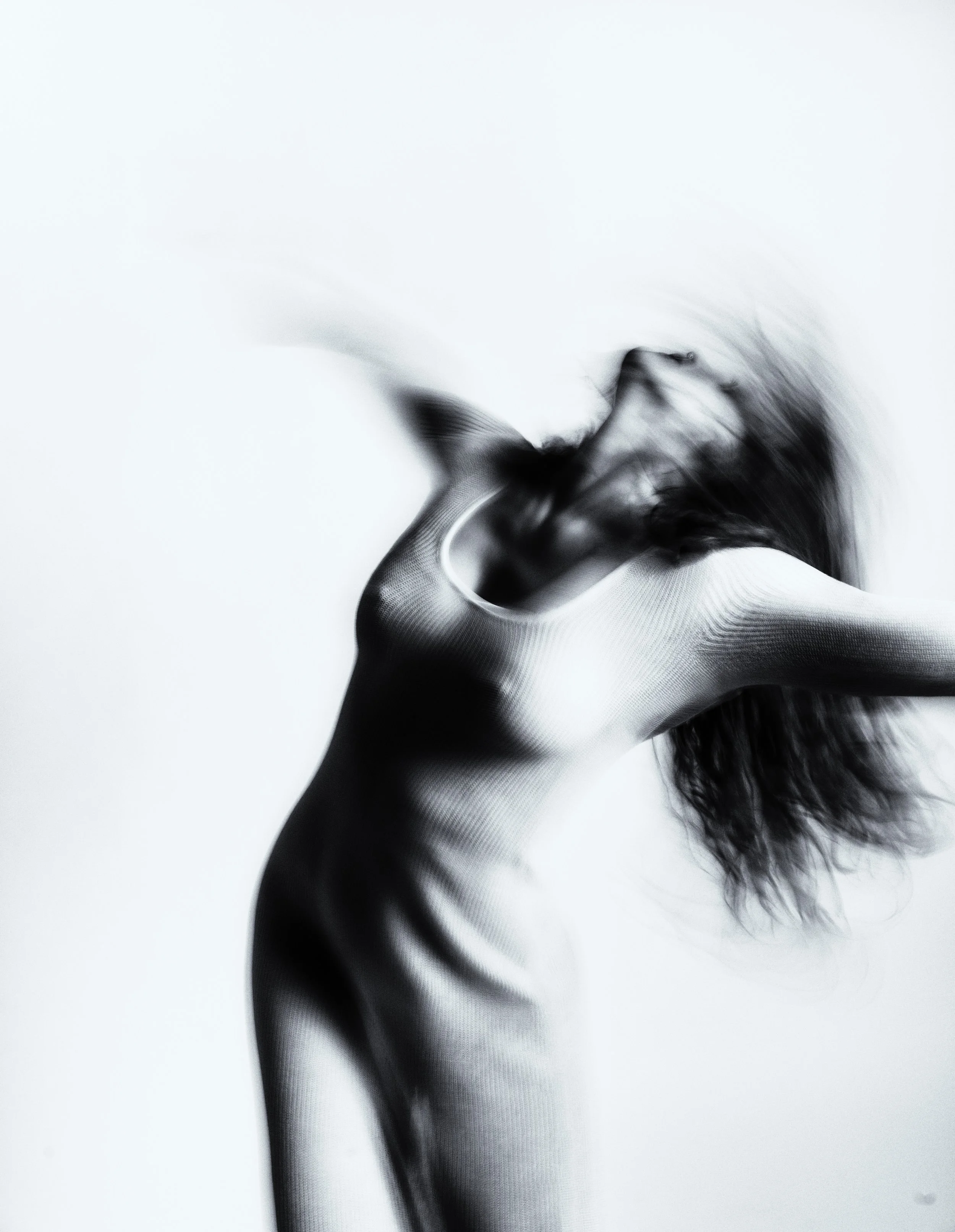 Abstract black and white blurred image of a woman with long hair, creating a dynamic movement effect.