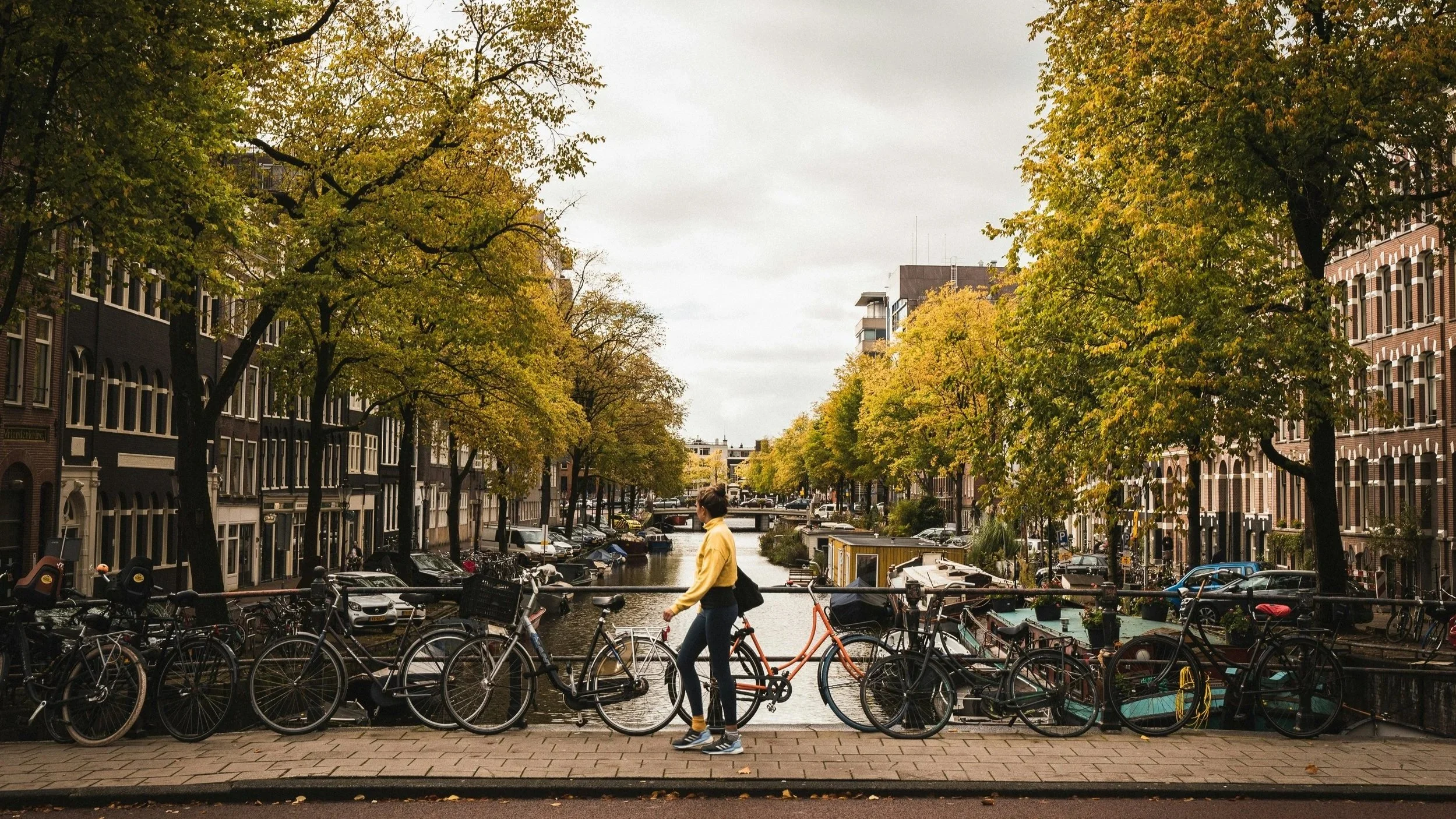 Woman walking alone across a bridge over a canal in the Netherlands in autumn