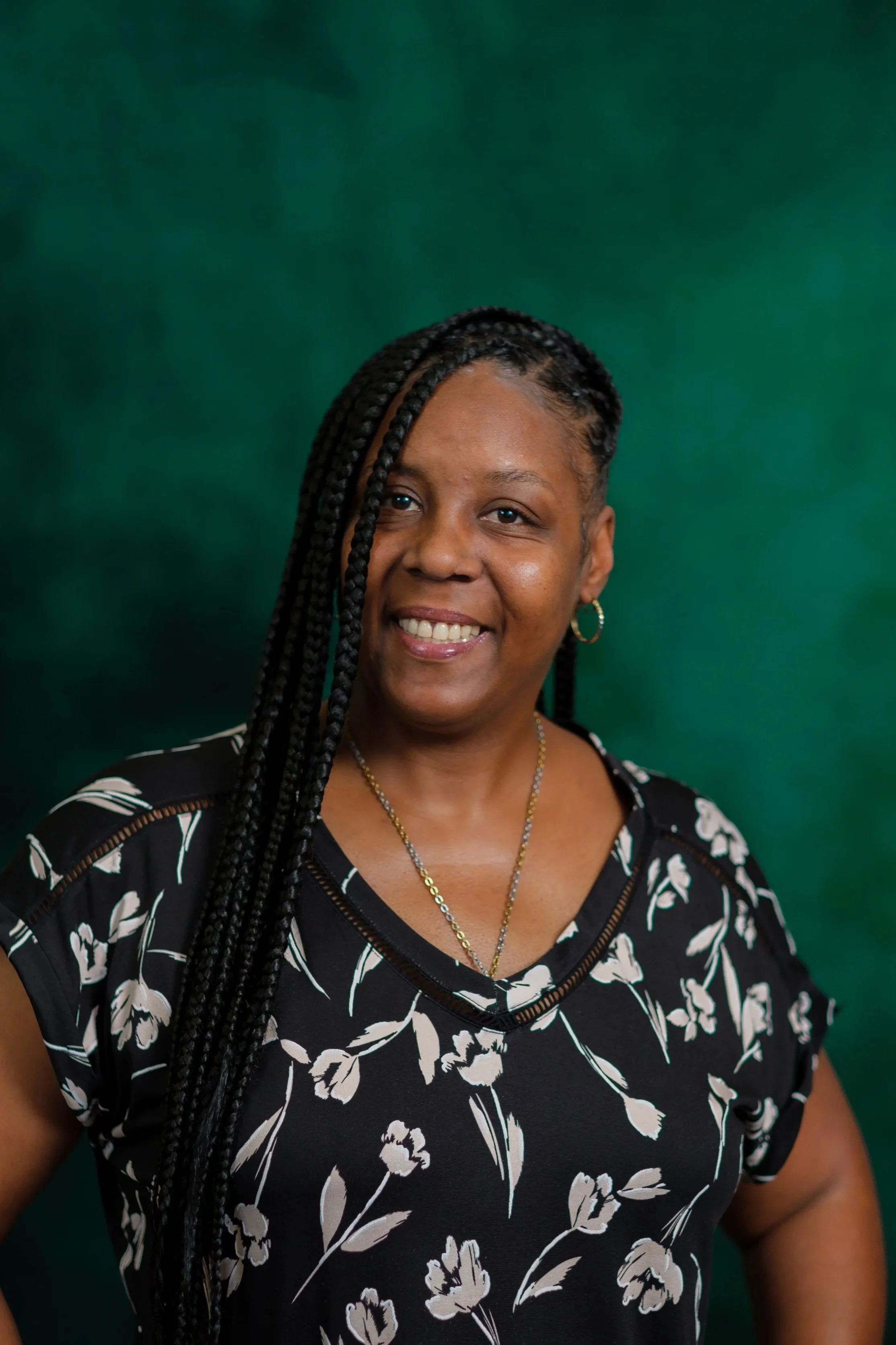 A smiling woman wearing a green t-shirt with the words 'Diversion HKB' printed on it, standing against a green backdrop.