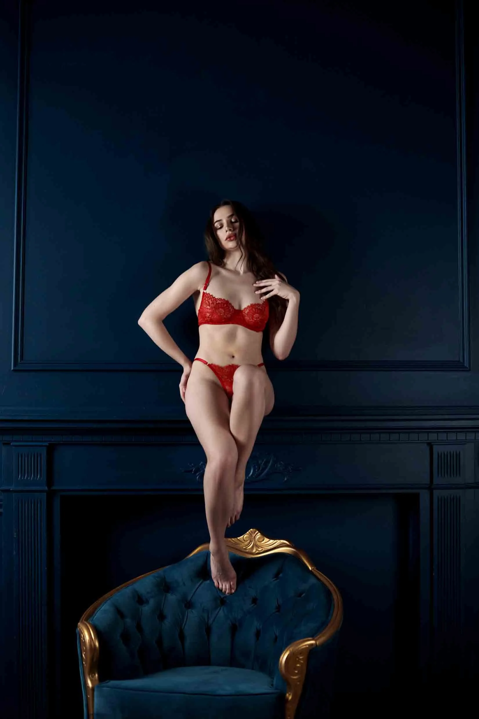 Girl in red lingerie sitting o a fireplace