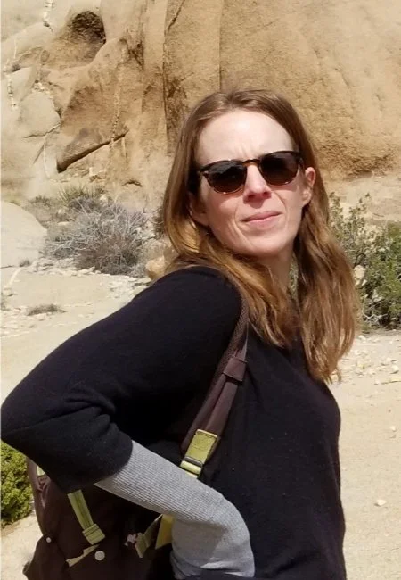 Christina Henry de Tessan on a hike with sunglasses and carrying a backpack