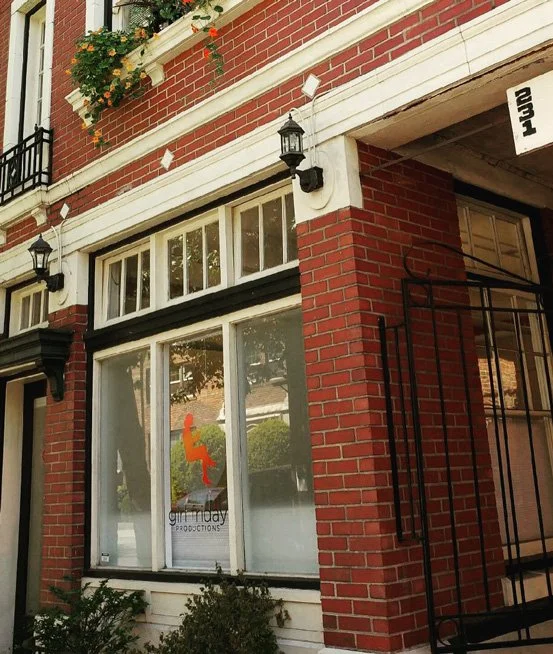 The front of a brick building with the Girl Friday Productions logo in the window