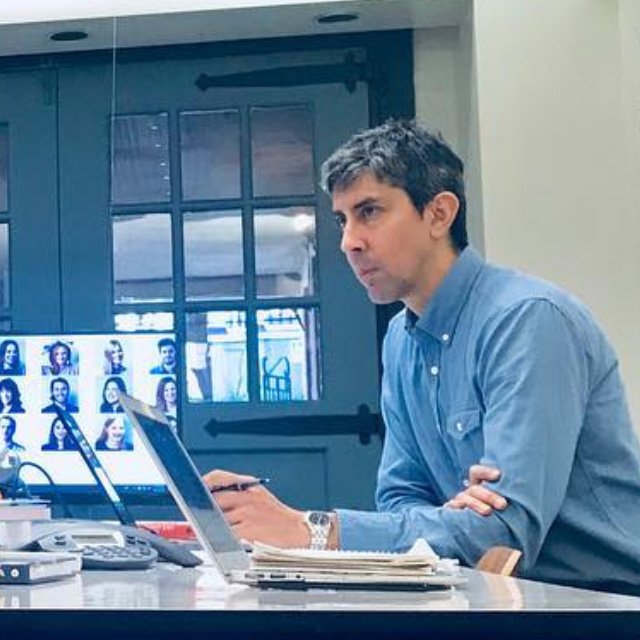Dave Valencia sits at a table in a conference room with several laptops