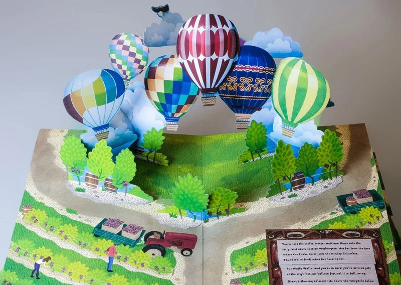 A spread from the Wings Over Washington pop-up children's book, featuring hot air balloons over a farm field