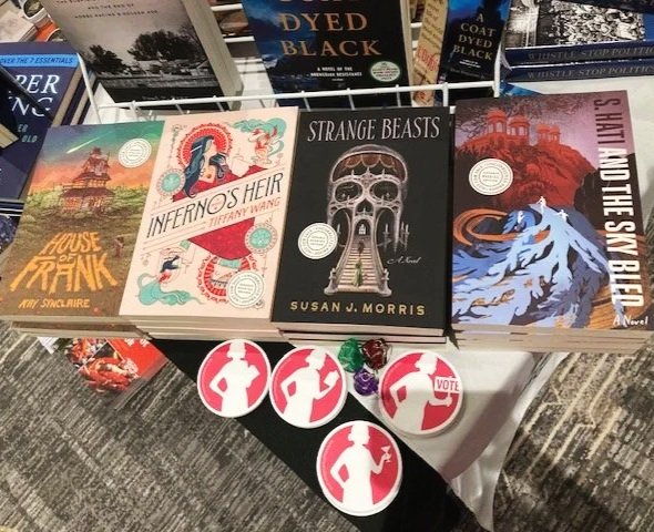 Four paperback books from Bindery Books lay on a table with Girl Friday Productions stickers scattered around