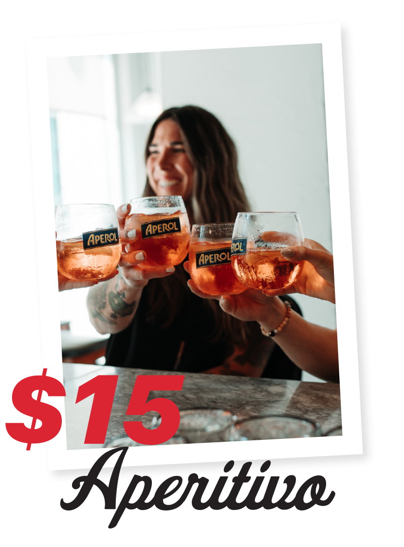 A woman smiling and holding glasses of Aperol spritz to celebrate, with a promotional sign displaying $15
