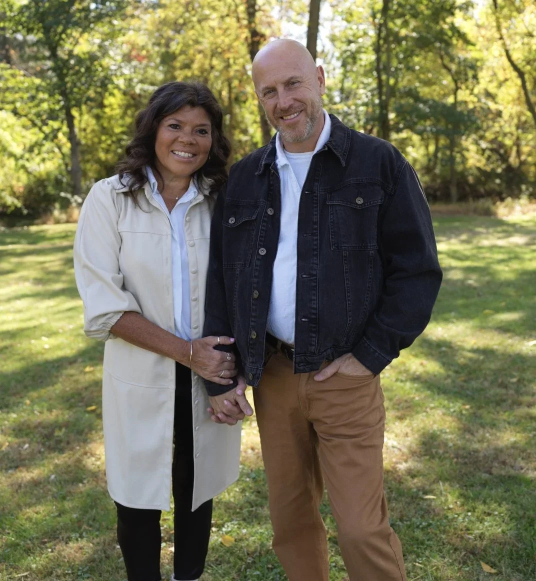 A smiling couple holding hands outdoors in a park during daytime.