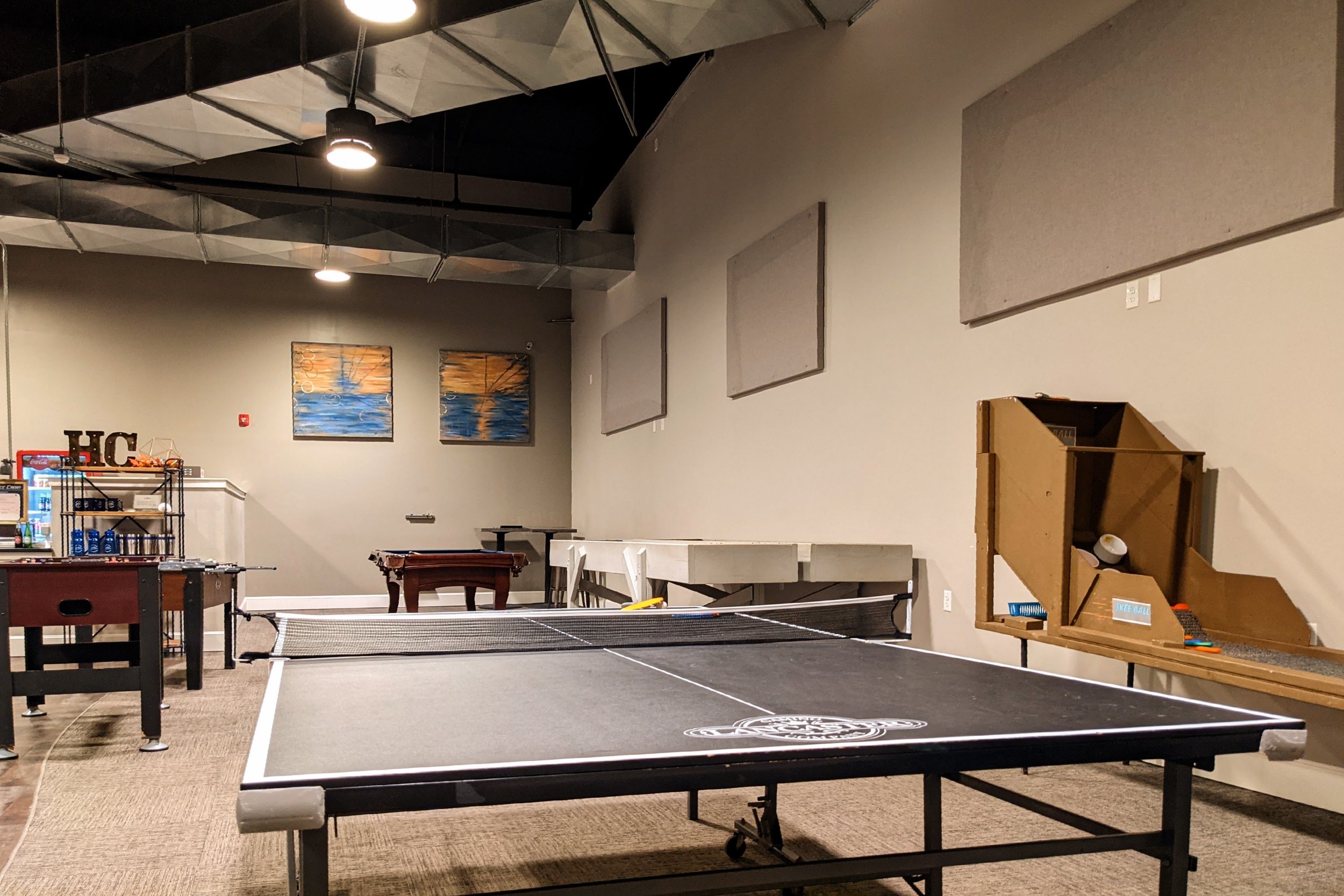 Indoor recreational room with a ping pong table, foosball table, pool table, and various wall decorations.