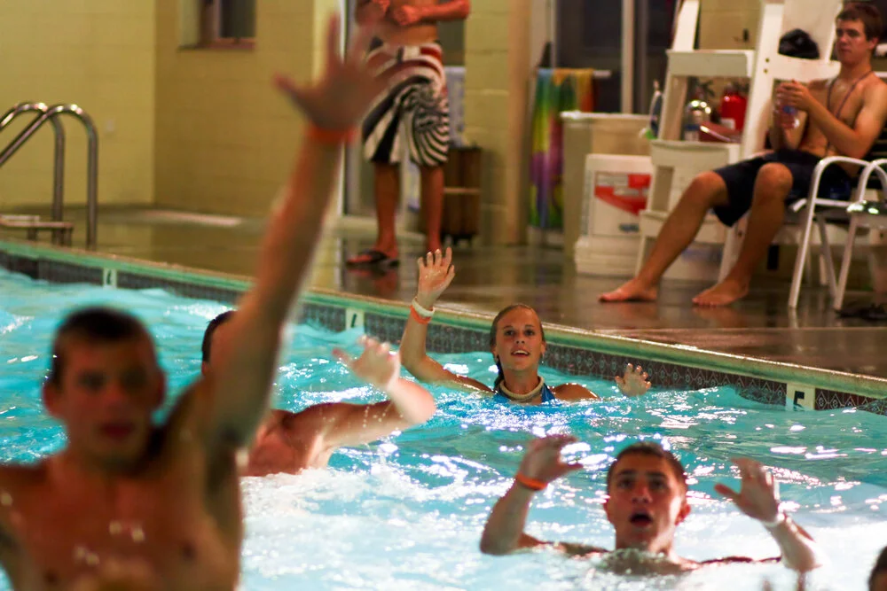 Swimmers in a swimming pool raising their hands.
