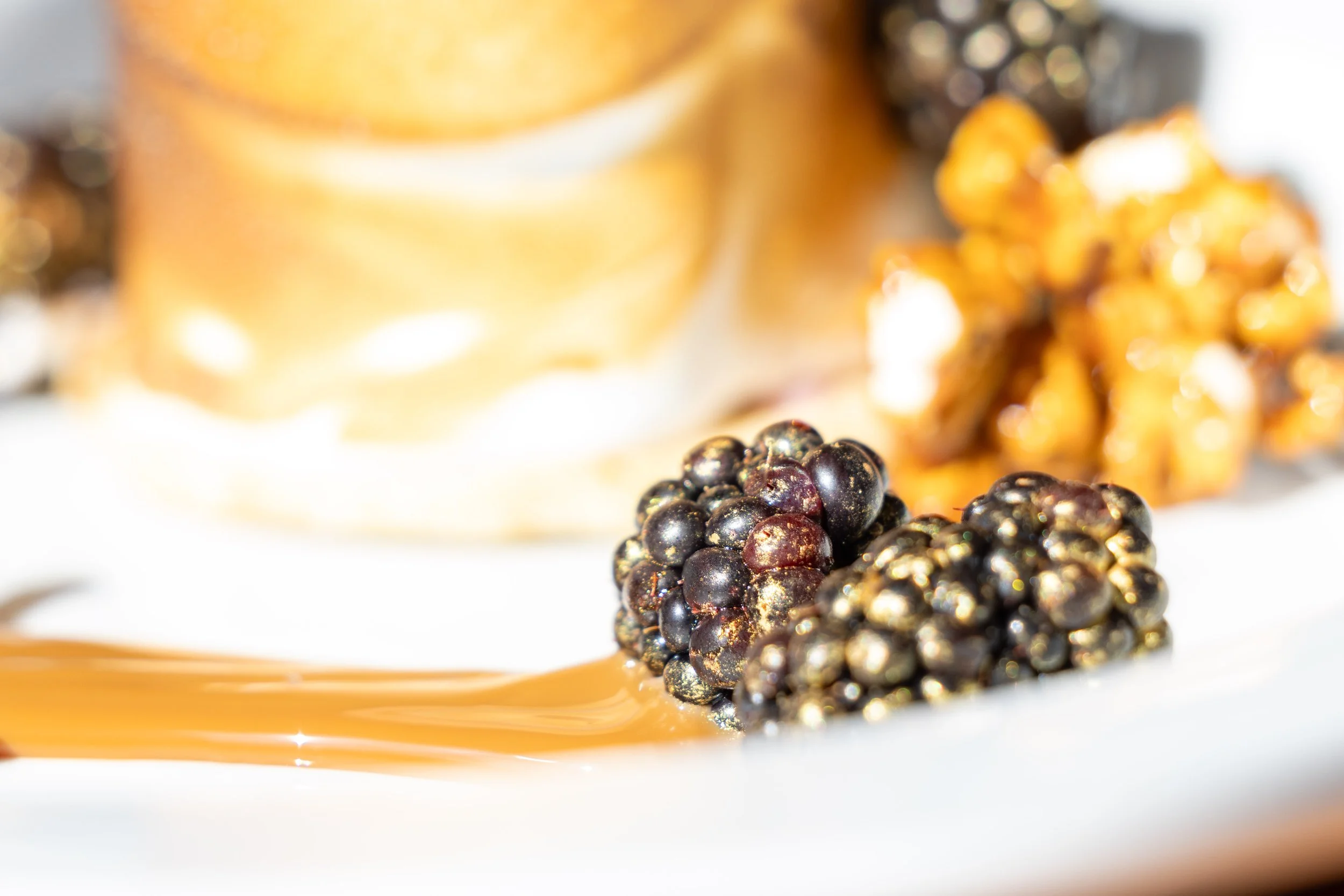 Close up of a gold dusted blackberry as part of the Baked Alaska dessert
