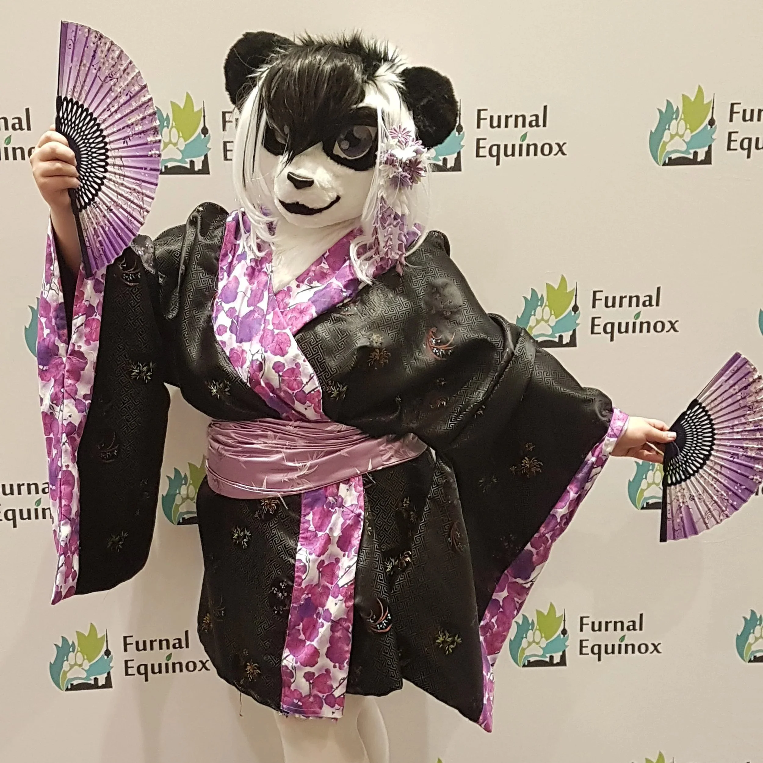 Costumed panda mascot wearing a traditional Japanese kimono holding a pink and purple fan against a backdrop with the text 'Furnal Equinox' and a stylized plant logo.