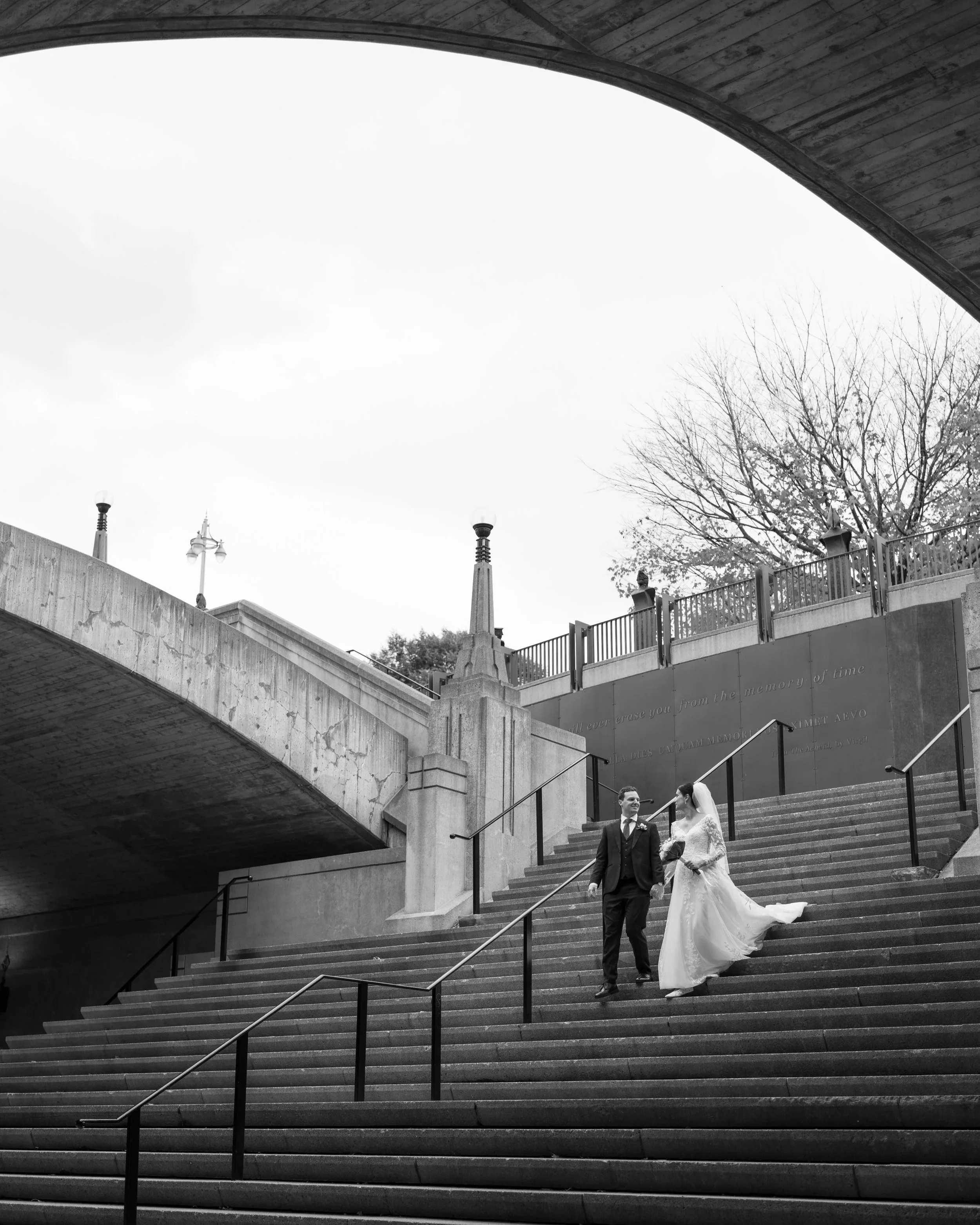 Black and white portrait of the bride and groom walking down outdoor stairs in Ottawa.