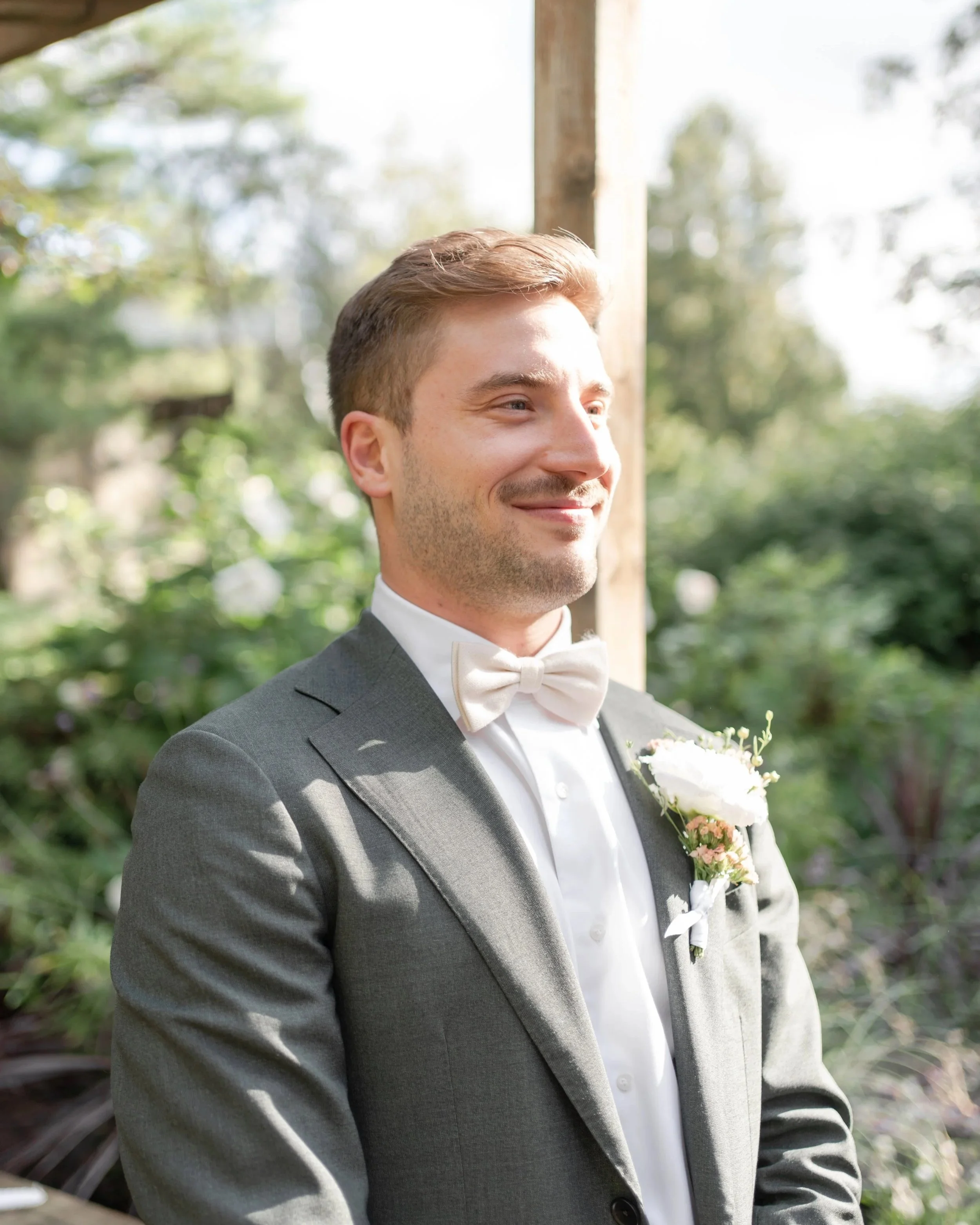 A smiling man in a gray suit during the outdoor ceremony. La Toundra, Montreal, QC