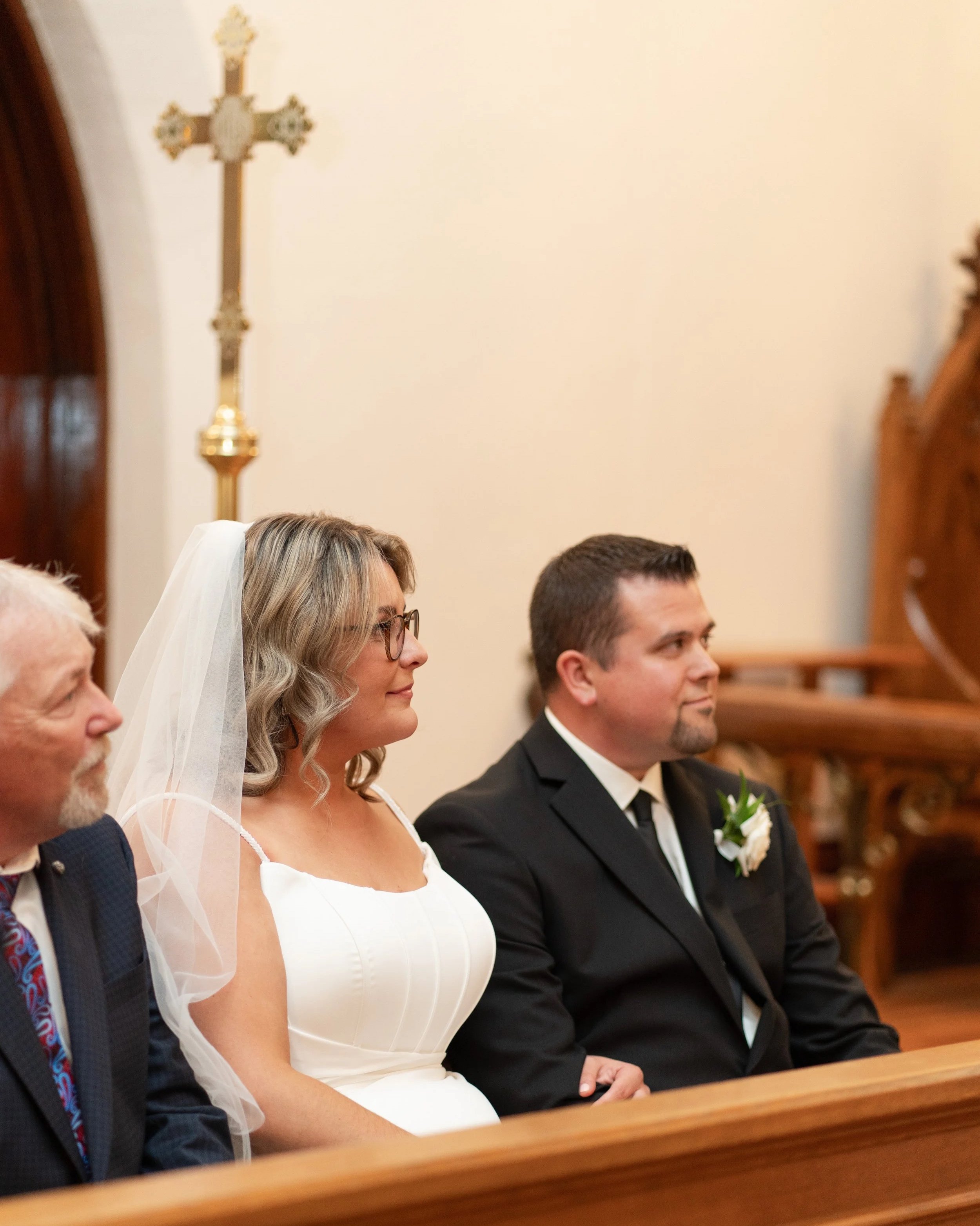 A bride and groom sitting side by side in a church during their wedding ceremony. Pembroke church