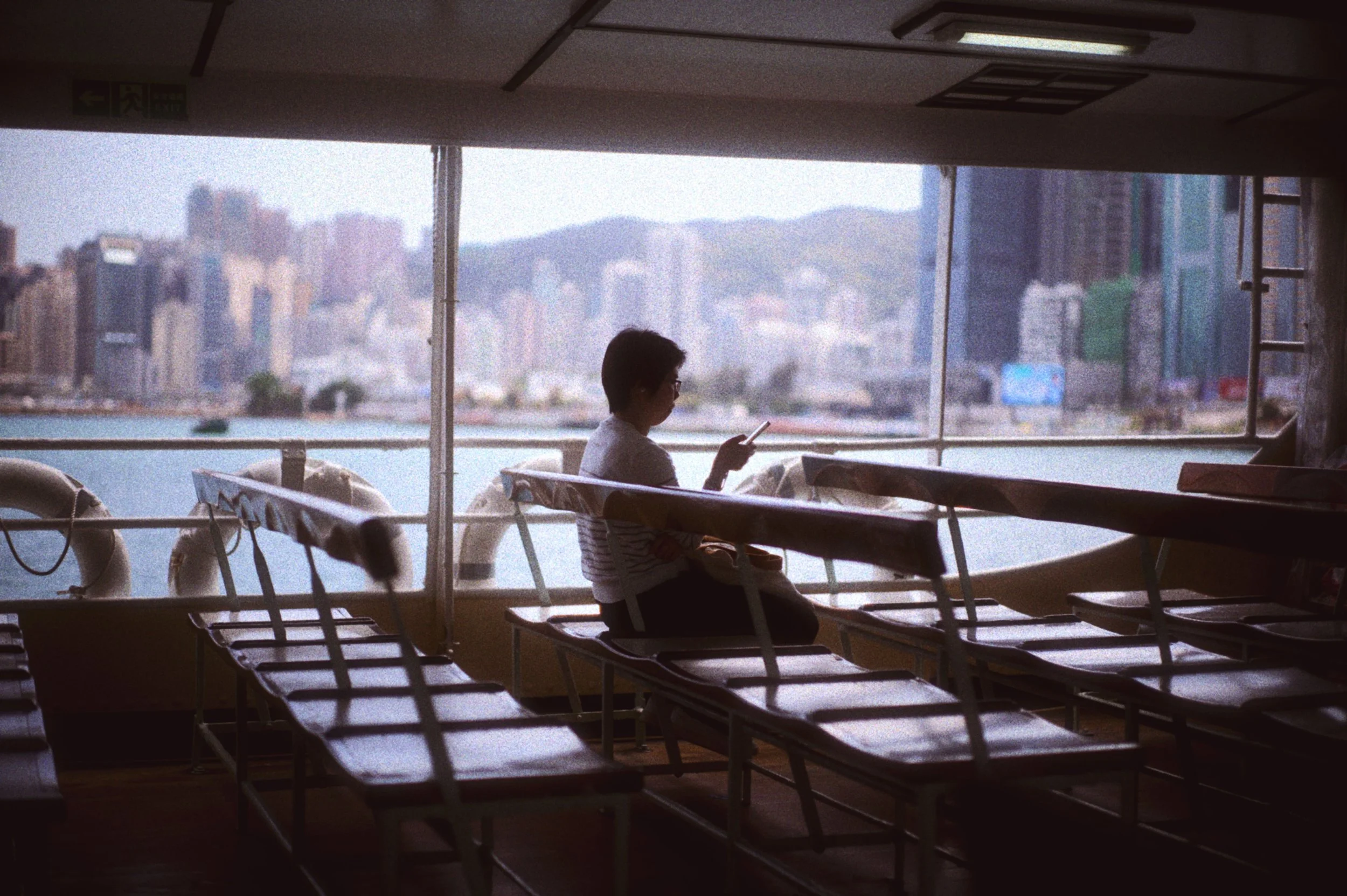 A commuter using a mobile smartphone onboard the Star Ferry in Hong Kong, representing daily mobile digital engagement.