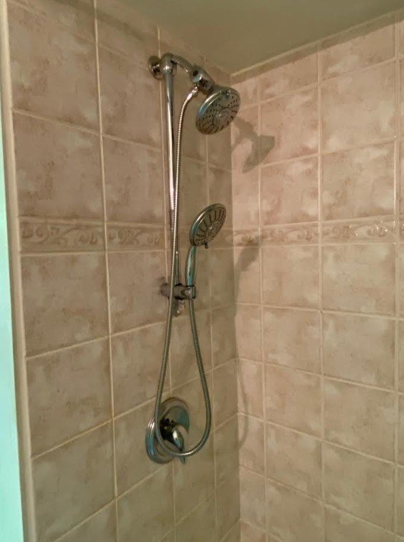Dated shower tile and fixture from the early 2000s Tuscan look.