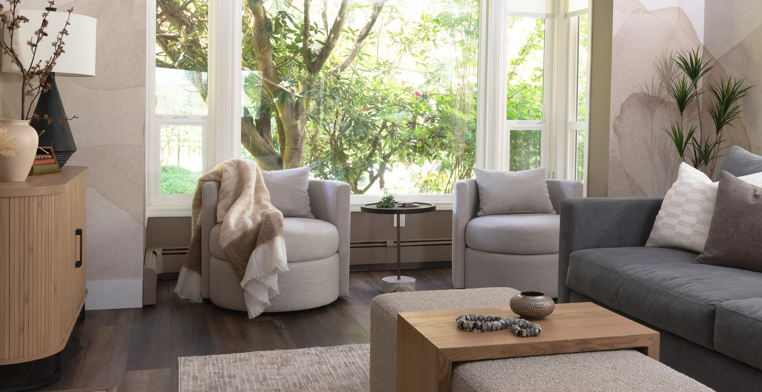 A pair of Van Gogh Olive Swivel Chairs customized with a Maxwell fabric are the stars of this updated living room with new blue sofa and greige fabric ottoman with sliding white oak C-table top.