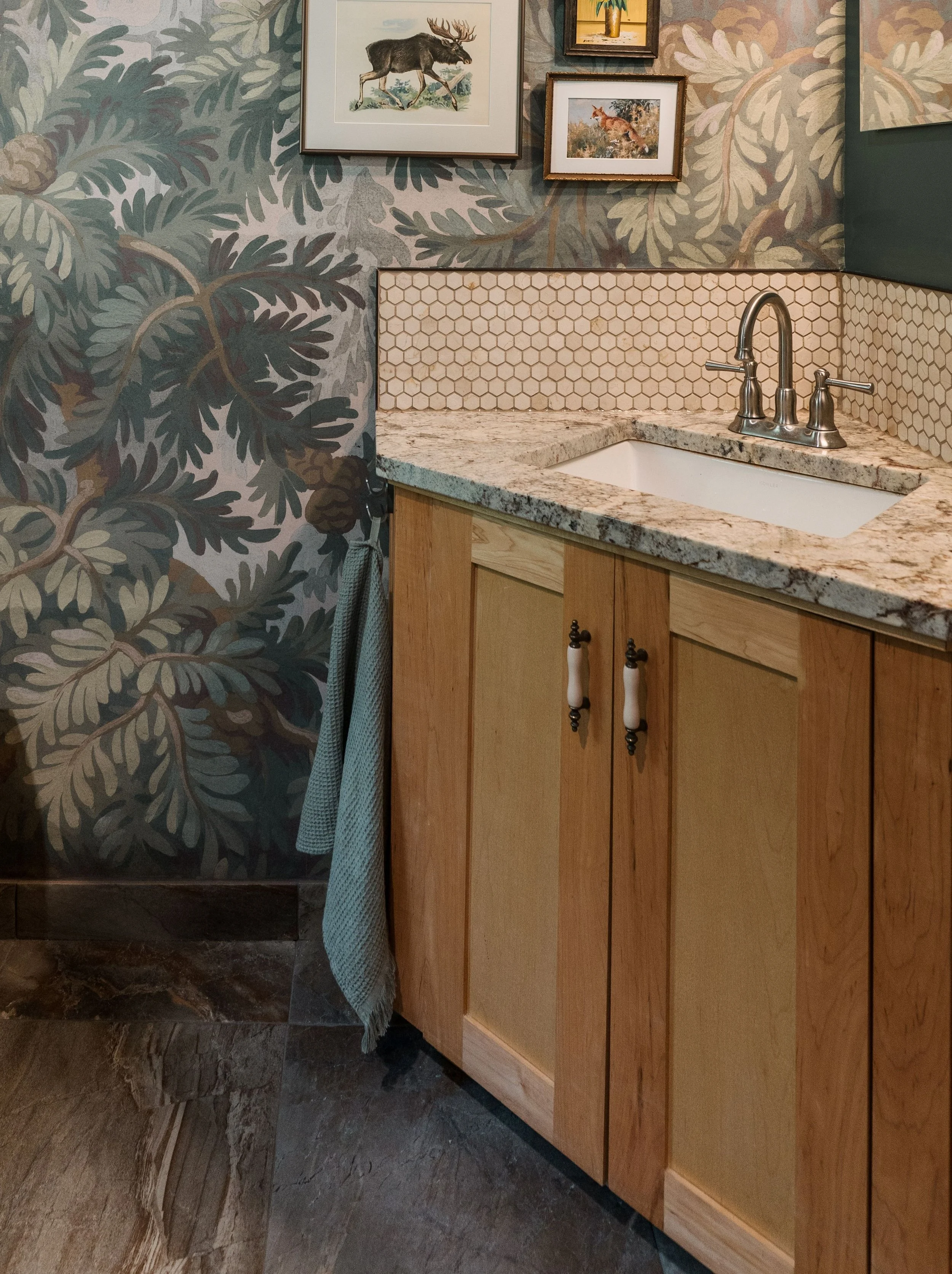 A light birch colored bathroom vanity is recycled and repurposed in a cabin's brand new build in order to help the new bathroom blend with the old cabin which is mainly warm pine throughout the cabin. Spruce Wallpaper Rebel Walls and vintage art.