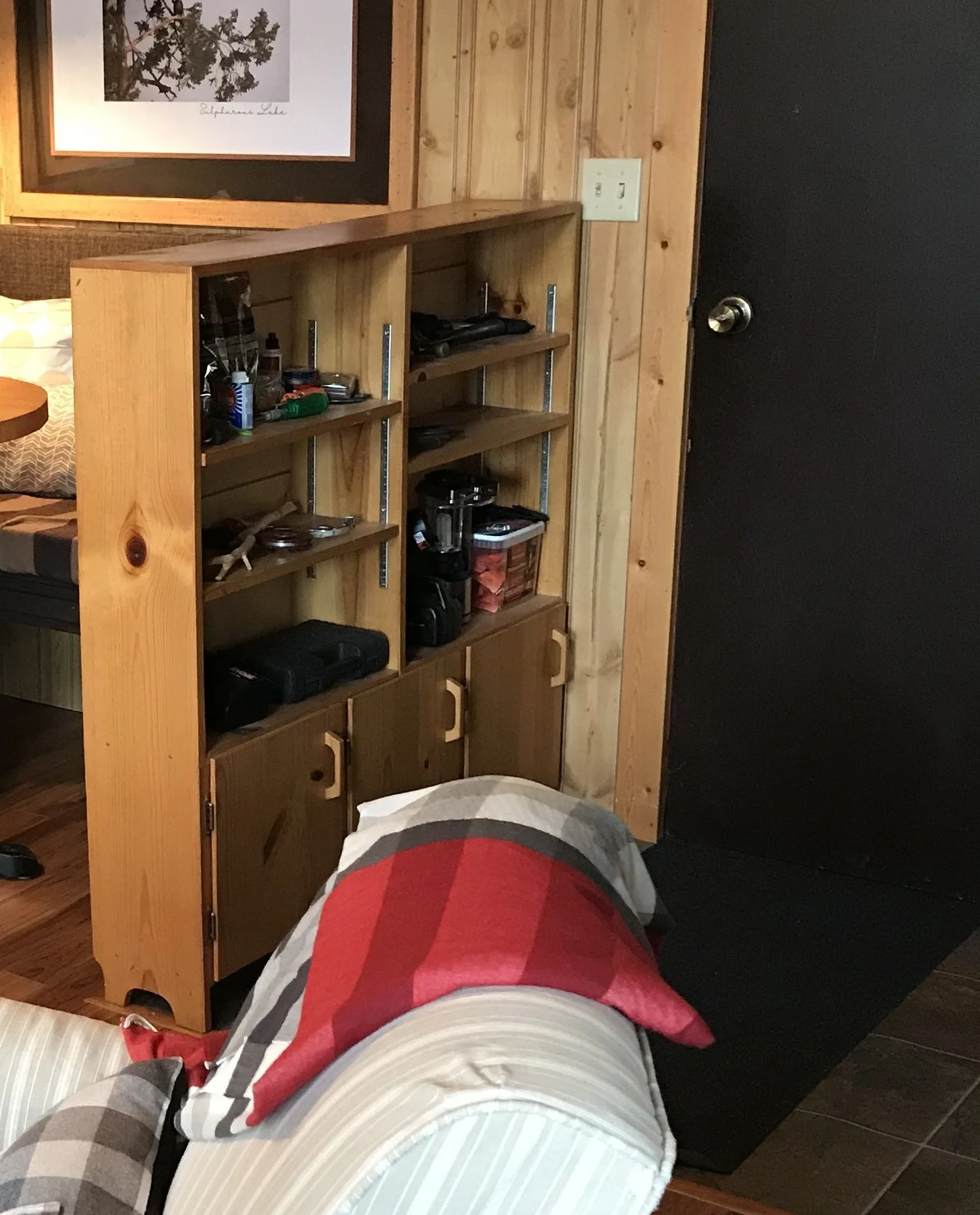 An extremely narrow shelving unit of about 8" wide and about 48"wide and tall, stands right at the cabin's back door and houses all of the junk and stuff that comes and goes. Light headlamps, lighter, batteries, etc.