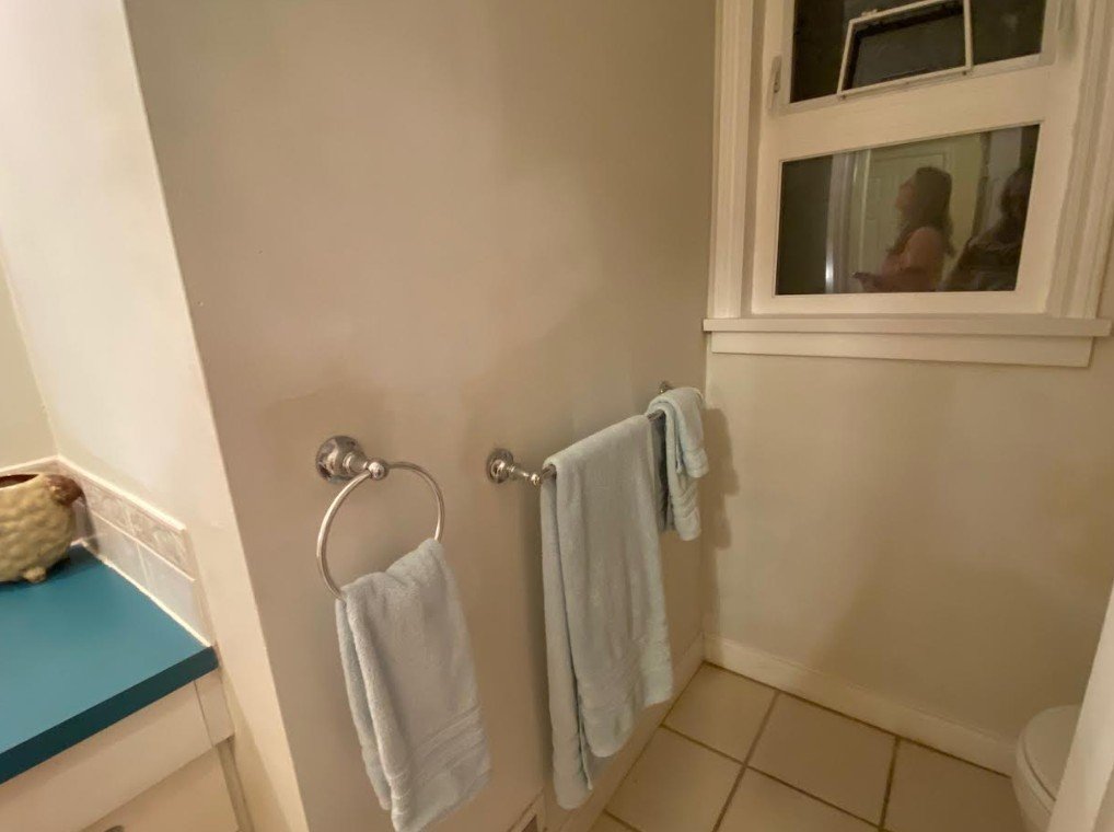 Hand towel in a dated bathroom takes up wall space where a proper towel rack could go.